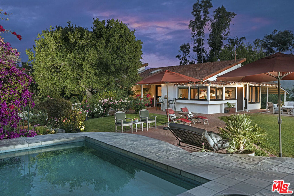 The School Road Ranch is not just a home-it's a living, breathing experience of Topanga Canyon life at its most soulful. Perched gracefully on a gentle knoll in the heart of the Canyon, this 1.85 acre sprawling compound offers a rare blend of privacy, creativity, and connection to nature. Here, warm southern light filters through ancient oaks, cool ocean breezes drift up from the Pacific, and expansive canyon views unfold in every direction. The property spans nearly 2 acres of vibrant, usable land, a sanctuary where families, artists, and seekers of beauty can truly thrive. From the moment you step through the rustic wooden gate, the outside world dissolves. You're greeted by rolling green lawns, flowering native gardens alive with hummingbirds, and winding pathways that lead to secret spaces: a hidden bamboo forest, decks suspended in the view, and sun-drenched spots perfect for reflection or shared meals under the sky. This is a place where children can run barefoot, where creativity has room to breathe, and where life slows down to meet the rhythms of nature. The main house has been reimagined with reverence for craftsmanship and texture, honoring both the land and a lineage of soulful design, creating a space of peace and tranquility. Reclaimed wood ceilings, handmade Indonesian carved doors, and artisan windows frame the changing light throughout the day. The great room welcomes you with soaring open-beamed ceilings, a glowing fireplace, and wide plank oak floors that invite bare feet and long, quiet mornings. The kitchen is both functional and inspirational outfitted with True, Viking, and Sub-Zero appliances offering space to create nourishing meals with family and friends. The primary suite is more than a bedroom; it's a retreat for the spirit, designed as an open-concept sanctuary where rest, reflection, and renewal happen naturally. Soak in the deep copper tub while gazing at distant mountain views, step onto the private sun deck after a restorative bath, or slide the handcrafted wall to create quiet separation when needed. Two additional bedrooms and a thoughtfully designed bath complete the main home, offering comfort and flow for loved ones. Scattered across the property are spaces designed for creativity, connection, and quiet solitude. Two fully self-contained guest units each with private entrances, kitchenettes, and baths are perfect for visiting family, creative residencies, or generating rental income while maintaining privacy. One guest house features a separate sleeping area with warm hardwood floors and custom finishes; the other offers an open studio layout ideal for writing, painting, or quiet retreat. An additional office cabin, potting shed, and secret gardens woven throughout the landscape provide endless opportunities for discovery and reflection. The grounds have inspired countless fashion and product shoots, but the true beauty is how naturally life unfolds here: dinners under the stars, early morning swims, trails that lead to new ideas, and spaces that hold both community and solitude in balance. 22068 Topanga School Road is a property for those who value intention, beauty, and belonging. It's for those who want to grow together in nature, for artists seeking inspiration, and for travelers ready to root themselves in a place where creativity, consciousness, and connection to the earth are part of daily life. This is the Topanga Life fully realized.