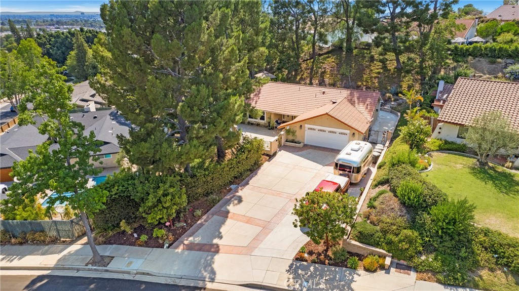 Tucked into the foothills of Orange, this thoughtfully remodeled single-level home is a rare find. Enter through a charming Hacienda-style courtyard with no steps from the driveway to the front door, ensuring easy access for all. Inside, the spacious open-concept great room features a cozy brick fireplace and flows seamlessly into a stunning chef’s kitchen. Recently updated, the light and bright kitchen boasts sleek black appliances, crisp white cabinetry, gray quartz countertops, self-closing drawers and cabinets, and a generous center island—ideal for both cooking and gathering. The adjacent dining area comfortably accommodates large groups, making it perfect for entertaining. From the great room, step out onto a large, step-free patio—perfect for relaxing, dining al fresco, or hosting guests. A central hallway leads to three spacious bedrooms and two remodeled bathrooms, including a stylish guest bath and a beautifully upgraded primary ensuite. The home is move-in ready, featuring manufactured wood flooring and fresh interior paint throughout. The air conditioning and heater have also been recently updated. Situated on a generous 12,600 sq ft lot, the backyard is a private retreat with mature fruit trees— many different varieties of citrus, plus avocado and fig—along with city and hillside views, multiple sitting areas, and meandering garden pathways that invite you to explore and unwind. Additional highlights include ample driveway parking with RV parking. Conveniently located near top-rated schools, shopping, and with easy freeway access, this home combines comfort, style, and a prime location, - truly offering the best of Orange living.
