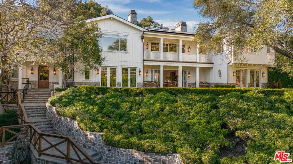 Step behind a discreet gate and enter into what truly feels like a private oasis. The sound of a gentle stream water feature provides an immediate sense of calm, and you are welcomed by views of the most unimaginable park-like setting. Offering 3/4 of an acre of land, pathways of natural stone invite you to multiple grass areas for relaxation and play, a sports court, and a lower pool area with guest-house. The owners worked with interior design firm, Maurice Gadson, on this extensive renovation and transformed the main residence into a living space that celebrates simplicity and beauty, surrounded by a level of quality and curated design that we do not have the pleasure of seeing every day. You will be inspired by the colors, craftsmanship, and attention to detail throughout. The stunning kitchen and main living room are the heart of the home, offering dramatic pitched ceiling lines and seamless access to the gardens and outdoor living spaces. The custom wood paneled media room and secondary family room were designed as flexible spaces for work and play. No detail was spared with Samuel Heath and Waterworks fixtures, French vintage exterior lighting, fabrics by Holly Hunt, Thomas Lavin, and Schumacher throughout, integrated Missoni runners, rich Calcutta stone countertops, custom-finished millwork, Christian Lacroix wallpaper, automated shades throughout, and a smart home automation system. The outdoor kitchen and dining area offer a beautiful elevated outdoor entertaining experience. In the evenings, one can hear the calming sounds of the owls and birds chirping into the night, all while enjoying the gorgeous outdoor fireplace and views of the property's charming vineyard. The experience simply cannot be replicated.