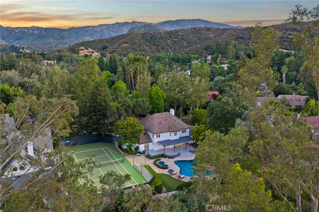 Stunning tennis court estate located at the base of the scenic Santa Monica Mountains, within the prestigious Countryside Estates community, adjacent to Paramount Ranch. Set on approximately one acre of lush, landscaped grounds, this home offers the ultimate in privacy, comfort, and resort-style living.
Step into your own private backyard oasis—perfect for entertaining or unwinding in paradise. Enjoy a full-size lighted tennis court, putting green, and a sparkling swimming pool with a waterfall and spa. Mature landscaping includes oak trees, redwoods, and 30+ rose trees.
Inside, the home boasts 5 spacious bedrooms, including a junior suite on the main level with its own sitting area and ensuite bath—ideal for guests or multigenerational living. Upstairs, the primary suite features two walk-in closets, a private patio, and a cozy gas fireplace. Two additional fireplaces warm the formal living room and family room, adding ambiance throughout.
The upgraded kitchen is a chef’s dream with stainless steel appliances, a Thermador cooktop, and double oven. Recent improvements include new windows with 50/50 wide-plank plantation shutters, flooring, hand-made glass chandeliers, and whole home filtered water system, blending modern updates with timeless elegance.
Situated on a peaceful cul-de-sac, the semi-circular driveway offers ample guest parking and plenty of space for RV parking. The third-car garage has been transformed into a fully equipped fitness/yoga studio.
This exceptional property combines luxurious amenities, privacy, and an unbeatable location—truly a rare offering in one of the most desirable neighborhoods.