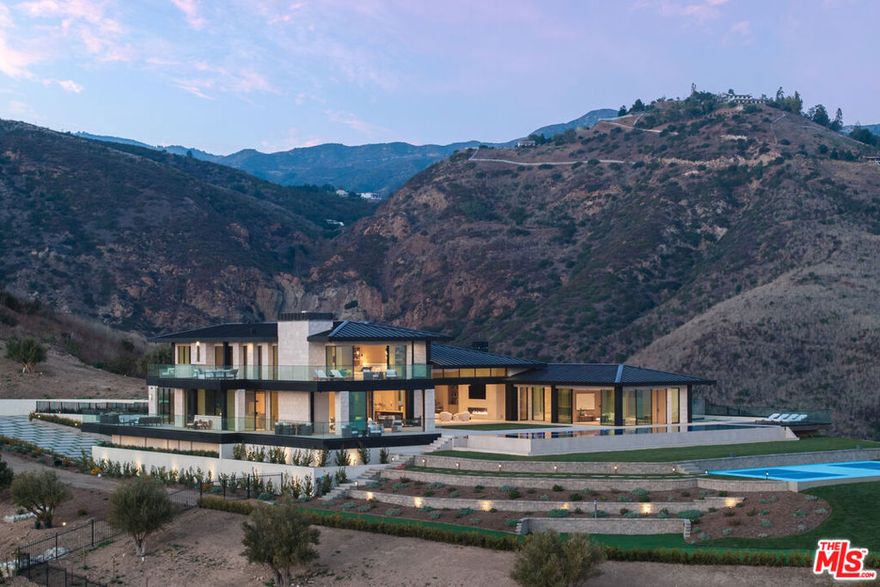 Introducing 6050 Murphy Way in Malibuan extraordinary, newly built residence perched above Paradise Cove. Set on two parcels totalling nearly 21.5 acres, and offering 10,700 square feet of ultra-contemporary design and complete privacyboasting sweeping, unobstructed views from Santa Monica to Leo Carrillo Beach. This architectural masterpiece by Brian Biglin of Biglin Architectural Group sits at the end of a long, gated driveway that lends an exclusive sense of arrival. As you step inside, you're welcomed into a soaring, double-height great room flooded with natural light and panoramic ocean, coastline, and mountain views. The home's design and open floor plan embrace the natural beauty of its surroundings, with meticulous attention to light, space, and proportion. Floor-to-ceiling glass walls draw the horizon and ocean views into every room while disappearing Cortizzo sliding doors open to the outdoor terraces for seamless indoor-outdoor living. An interior palette of white oak floors, white oak veneer walls and doors, and limestone accents establish a sense of serenity throughout. The main living area is anchored by a spectacular 100-foot custom gas fireplace. A dramatic wine display showcases up to 300 bottles and provides an artful centerpiece to the adjacent dining area. An adjacent marble-clad bar, crafted from Patagonia quartzite, sets the tone for elegant entertaining. Custom chandeliers and carefully chosen light fixtures are expressions of the home's minimalist elegance, while a floating staircase adds sculptural detail. The chef's kitchen with adjoining butler's pantry features Jurassic marble countertops, Italian Mia Tessa motorized cabinetry, Miele and Gaggenau appliances, and a bold black accent wall that contrasts beautifully with the room's light wood tones. Additional living spaces on the main level open to the expansive terrace, where a 74-foot infinity-edge pool and spa overlook the Pacific Ocean. The terraced outdoor spaces include a pickleball court, a putting green, custom Trex decking, and multiple lounge areas for entertaining or unwinding under the stars. Upstairs, the primary suite is a peaceful oasis with unmatched views, private terrace, an 80-foot gas fireplace, walk-in closet, and a spa-like bathroom designed for two with a sculptural soaker tub, Brizo fixtures and a private terrace. An upstairs office with patio, a luxuriously appointed theatre room with plush shagreen velvet wall coverings, and additional ensuite bedrooms adorned with travertine and blue onyx marble complete the home's second level. Enjoy a separate and flexible ADU currently built as a deluxe spa with red light Himalayan salt sauna. Other features include a home gym andControl4 smart home automation. The exterior is clad in custom split-face Italian limestone and metal fascia with tailored gutters, while the surrounding infrastructure includes a septic tank, erosion control systems, and a six-car garage. Additionally, a separate guest house up to 5,000 square feet is approved for a future build out. This rare offering combines sleek modern elegance with the ultimate in privacy in one of the most spectacular settings on the Malibu coast.