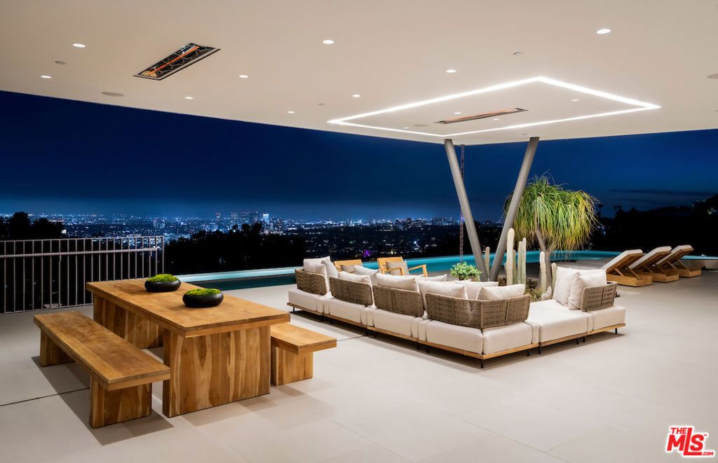 Step into the spotlight in this brand-new 13,500 SF contemporary masterpiece, perched in the legendary Bird Streets high above the Sunset Strip. Designed by the iconic Vantage Design Group, this architectural marvel of concrete and steel is a showpiece of style, sophistication, and luxury. Offering breathtaking panoramic views, this estate is a seamless blend of cutting-edge design, opulent indoor-outdoor living, and top-tier amenities, including two elevators (one is commercial-grade). Experience the grandeur of this home, starting with a cantilevered glass living room that appears to float above the city, leading to a sleek dining area and gourmet kitchen crafted for the most discerning chefs, featuring exquisite stone countertops and top-tier appliances. The high-tech family/media room boasts a statement bar and an immersive 12'x9' LED media wall, perfect for exclusive premieres or intimate gatherings. With 5 lavish bedrooms and 8 impeccably designed bathrooms, the primary suite offers a serene sitting area, spa-like ensuite with dual vanity, and a custom walk-in closet designed for refined elegance. Seamless floor-to-ceiling motorized Shuco glass doors open to an expansive 4,000 SF deck, where you can unwind by the sunken fire pit, bask in the glamour of the 175' infinity-edge pool with spa, Baja shelf, and sunken seating area, or entertain under the stars in ultimate style. Spanning 1.2 acres, this private sanctuary features drought-tolerant landscaping, 5,000 SF of lush gardens, meandering paths, and a citrus grove, all designed for balance and well-being. A fully equipped gym, yoga room, yoga terrace, and a spa with a sauna provide a retreat for relaxation and rejuvenation. This technologically advanced estate is equipped with Crestron full-home automation, individually climate-controlled wine rooms, automated blackout shades, and an eco-conscious solar power system, seamlessly blending sustainability and sophistication.
