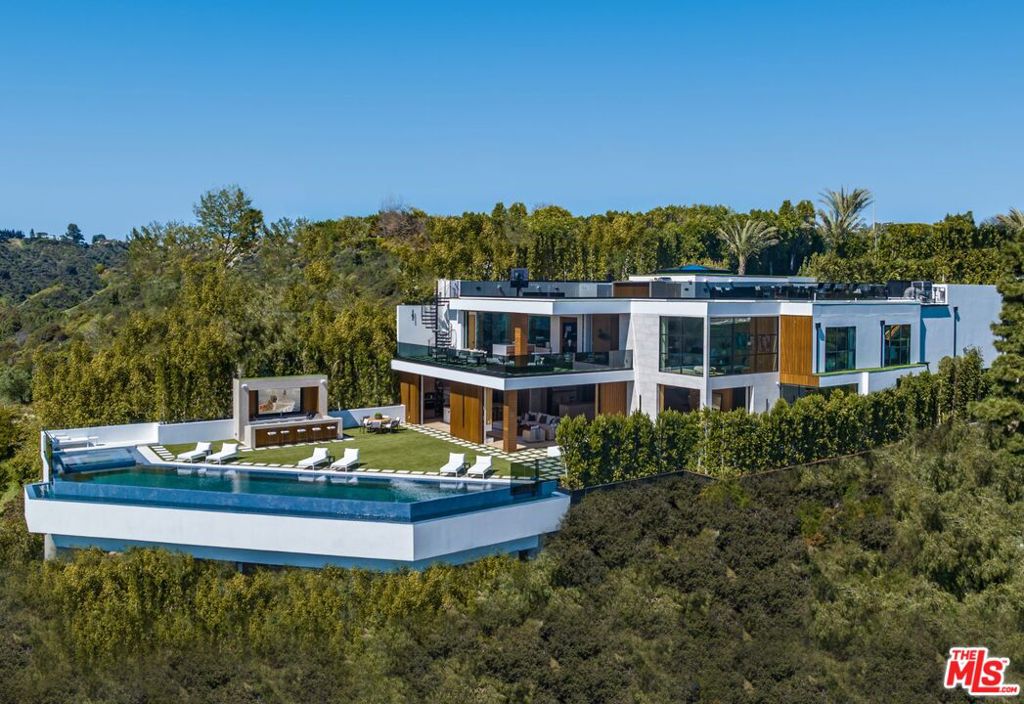 Welcome to Bel-Air Paradise, a brand-new estate, designed and built by the legendary Designer and Developer, Ramtin Ray Nosrati. Descend the private, gated driveway to this incredible oasis set in one of the most prestigious neighborhoods. The lush grounds and gated drive provide the utmost privacy and security. The oversized front door is flanked by walls of glass, wood, and a colorful living wall to create an unforgettable welcome. Step inside to experience the warm contemporary design, high-end finishes, show-stopping living wall, high ceilings, and panoramic ocean/city views. Automated Fleetwood glass doors open throughout the home to create a seamless indoor/outdoor lifestyle. The custom culinary center is a gourmand's dream, with state-of-the-art appliances, adjacent chef's prep area with restaurant-grade walk-in refrigerator, and oversized island. A travertine clad bar and stunning wine room with tasting area help to make this one of the most incredible homes for entertaining. The primary suite is complete with fireplace, wraparound deck with fire pit and sweeping views, spa-inspired bath with oversized rainwater shower, a Zen soaking tub, dual-sink vanity, and custom walk-in closet and dressing room. The latest and greatest amenities include a theater, gym, resort-style tropical landscaping, parking for 7 cars, smart-home system, and automated security. The outdoor oasis offers the perfect space for dining al fresco, outdoor kitchen with bar and flat-screen tv, flat grassy areas, spa, and a massive 80-foot zero-edge infinity-edge pool looking out to incredible city and ocean vistas. There is a large flat area that is perfect for adding a sports court, pickleball court, or tennis court. The outdoor space continues to the rooftop lounge with bar, large tv, fire pit, built-in BBQ, and putting green. Do not miss this opportunity to live at Bel-Air Paradise with jetliner views and incredible amenities in one of the most sought-after locations.