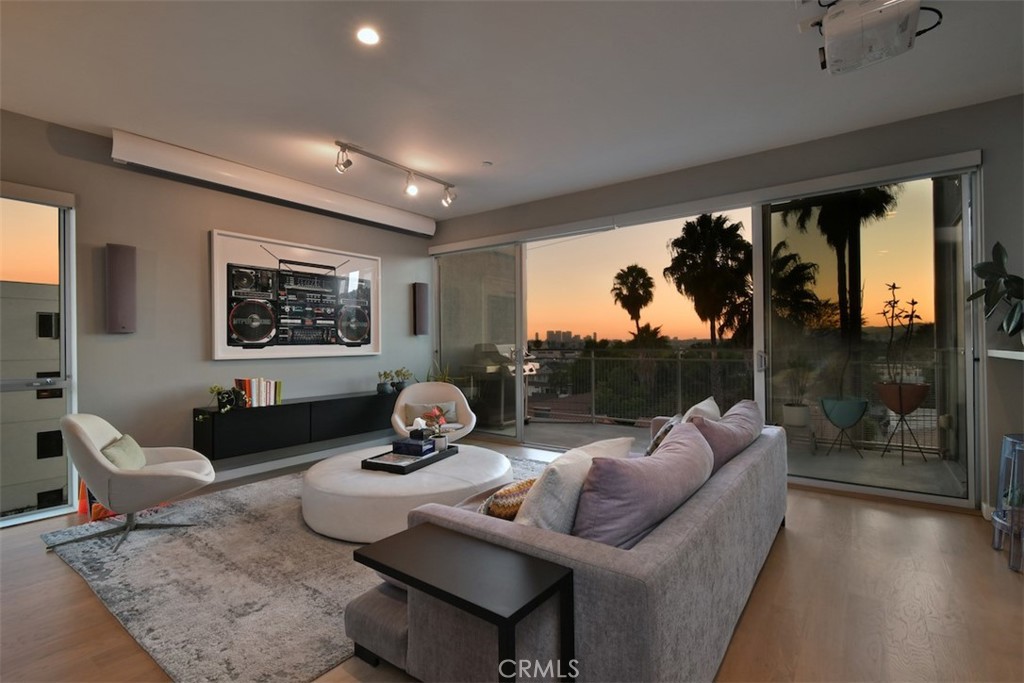 Live and work in style from this stunning 2,030 sq. ft. penthouse corner loft, offering dramatic unobstructed western and southern views stretching across the Hollywood Hills to Century City. Quietly tucked away on the quiet west side of the building—buffered from Fairfax traffic—this rare residence blends modern luxury with architectural pedigree and cutting-edge sustainable design.
Designed by the award-winning Brooks + Scarpa Architects, the development honors the site’s rich musical legacy as home to the legendary Cherokee Studios while pioneering green building practices. Completed in 2011, it became California’s first LEED Platinum–certified project of its kind.
The expansive open floor plan showcases soaring ceilings, hardwood floors, and floor-to-ceiling windows that flood the space with natural light. A sleek chef’s kitchen features white Caesarstone counters, stainless steel appliances, and a bar with beverage refrigerator—perfect for entertaining. The spacious primary suite includes a walk-in closet and spa-like en suite bath, a secondary guest bedroom, a dedicated office with breathtaking views which can easily be converted to a third bedroom, and a versatile flex space (currently used as an additional workspace and TV area) provide exceptional flexibility.
Recent upgrades enhance both the building and the unit. Building improvements include dedicated EV charging compatible with all electric cars and modernized access control. Inside the residence, thoughtful investments include a new 4K projector, automated shades, and a new washer. The home is heavily automated and Alexa-enabled, allowing voice control of lighting, shades, and entertainment.
Additional highlights include a BBQ with a direct gas line on the private terrace, surround sound throughout, LED lighting, tankless water heater, in-unit side-by-side laundry, and two generous storage areas (one on the balcony and another under the stairs). The building also features an expansive rooftop deck with panoramic 360-degree views of Los Angeles. Two side-by-side parking spaces are included.
Residents enjoy eco-conscious amenities, with HOA fees covering the building’s solar panel array, building insurance, and industrial-grade A/C system. Just steps away from West Hollywood’s most vibrant restaurants, bars, coffee shops, and fitness studios, this loft offers a rare opportunity for sophisticated, connected, and sustainable urban living.