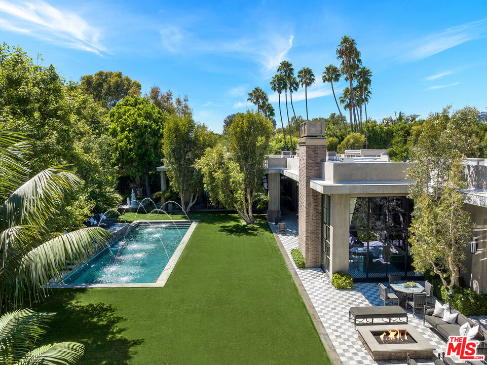 The Reserve is an extraordinary, architecturally significant estate situated on two ultra-private acres in the heart of Holmby Hills. Surrounded by swaying palm trees, lush forestry and immaculate landscaping, this secluded oasis is an exceptional vision of modernist architecture. The Reserve was recently refined by a team of expert designers and international craftsman who have carefully expanded the estate to create two properties that function for modern day living whilst exuding old Hollywood glamour. At 11,000-square feet on a single story, the main house's proportions are palatial. The ceilings are a spectacular 14-feet high, and vast floor-to ceiling windows offer uninterrupted views of the beautifully landscaped gardens, water features and the 50-foot swimming pool. Inside the house there are five spacious bedroom suites including a master wing, as well as a tremendous family kitchen/dining room, wine room, two magnificent living spaces featuring a Hollywood art deco bar and formal lounge for entertaining, a 1920s French regency-style cinema, a tranquil study and a spectacular playroom. The most significant addition to the estate is the three-story guest house. At 10,000-squarefeet, it is as luxurious and imposing as the main house, with five large bedroom suites, seven bathrooms, a kitchen and living area, gymnasium, spa, and a carport. It has been thoughtfully designed so that the lower level can operate as an independent apartment. The front of the property elegantly mirrors the exact style and dimensions of the main house, with majestic pillars and huge floor-to ceiling windows, while the rear of the house is an impressive three-story architectural spectacle, revealed through lush greenery.