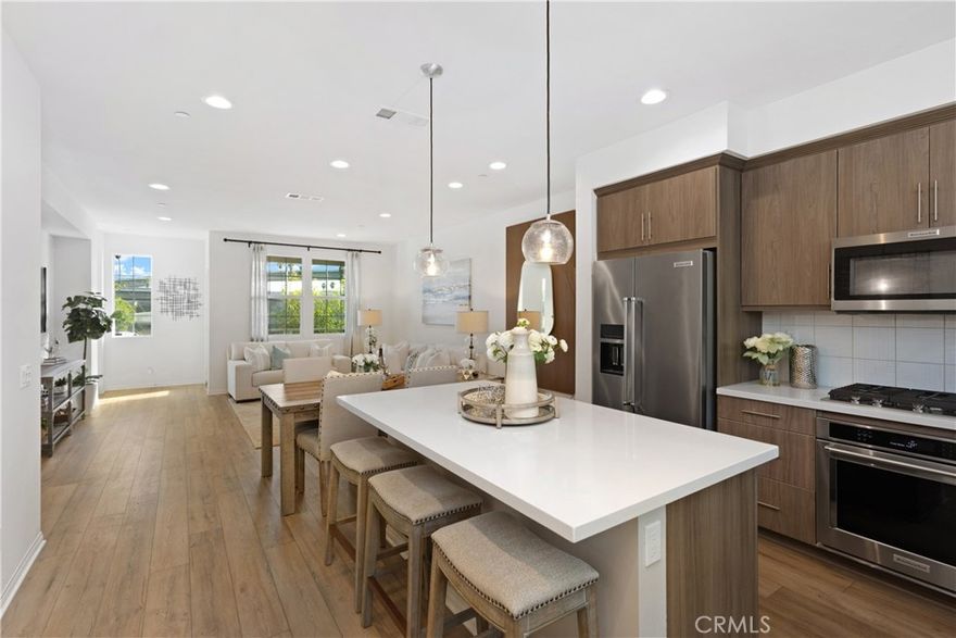 Step into this stunning tri-level townhome located in the highly desirable gated community of Magnolia Square in Buena Park. Designed with both style and functionality in mind, this spacious residence offers 4 bedrooms and 3.5 bathrooms, making it the perfect place to call home. The second floor showcases an open-concept living space with a gourmet kitchen that flows seamlessly into the dining and living areas ideal for both everyday living and entertaining guests. The kitchen is a true centerpiece, featuring quartz countertops, a large center island with seating, a walk-in pantry, and modern maple cabinetry. A private balcony invites you to relax outdoors, while a convenient powder room adds to the thoughtful layout. The third floor is dedicated to comfort, offering three spacious bedrooms and two full bathrooms. The primary suite feels like a retreat with its walk-in closet and bathroom complete with dual vanities and a large walk-in shower. Beautiful finishes enhance the home throughout, including laminate flooring on the first and second floors, plush carpeting in the bedrooms and stairs, and recessed lighting for a modern touch. Additional conveniences include an in-unit laundry room with washer and dryer, and an attached two-car garage with direct access. The gated front patio provides extra privacy and a welcoming outdoor space. Magnolia Square offers wonderful community amenities, including a children’s playground, BBQ area, and greenbelts for outdoor enjoyment. With no Mello-Roos, low HOA dues, and a prime location near the 5 and 91 freeways, this home provides the perfect blend of comfort, convenience, and value. Don’t miss your chance to tour this stylish, move-in-ready home in the heart of Buena Park schedule your private showing today!