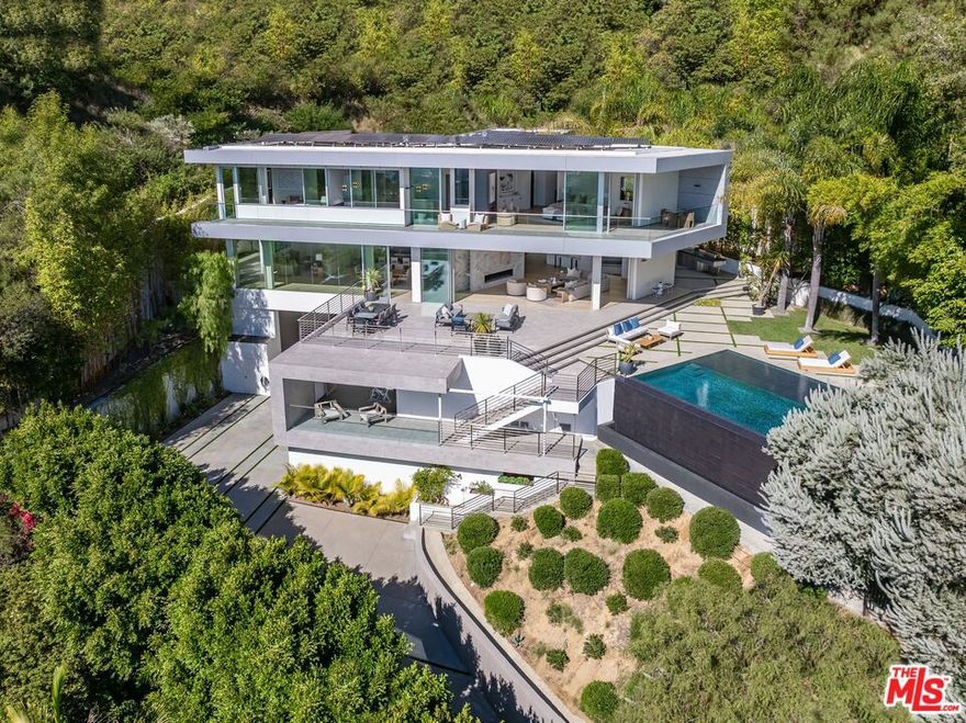 Perched at the top of Rising Glen, tucked away behind a private gate, sits this reimagined architectural estate. Spanning approximately 9,400 square feet, the 6-bedroom, 9-bathroom home blurs the line between indoor and outdoor living. Designed for entertaining on every scale, it features floor-to-ceiling glass walls that frame sweeping views from downtown to the ocean, filling each space with natural light. The open layout flows effortlessly to expansive terraces, outdoor dining areas, fireplaces, and an infinity-edge pool - creating a striking backdrop for gatherings. No detail has been overlooked - from the Poliform kitchen with Miele appliances to the elevator, gym, private theater, and temperature-controlled wine area. Every finish reflects thoughtful design, beautiful craftsmanship, and top-of-the-line construction throughout. With a 3-car garage, generous motor court parking, and total privacy just minutes from the heart of the city, this is a true modern sanctuary in the hills.