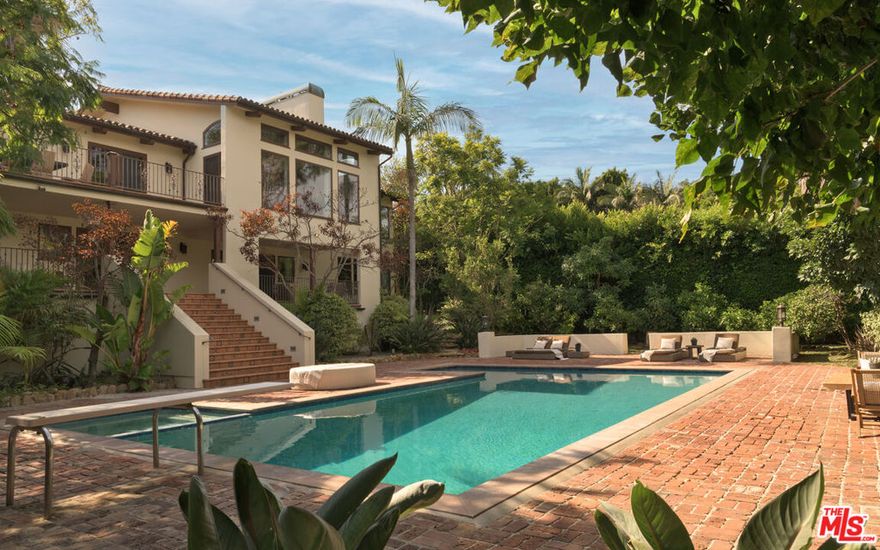 Nestled on one of Malibu's most prestigious streets, this gated estate offers an extraordinary blend of timeless Spanish architecture, refined interiors, and a resort-style outdoor lifestyle. Set on expansive grounds with a full-size tennis court, pool, and mature landscaping, the residence provides the rare opportunity to experience both elegance and comfort in one of Southern California's most sought-after coastal enclaves.The home is introduced by a broad stone motor court, lush gardens, and the classic silhouette of a Spanish-style villa with rustic clay tile rooflines. A graceful entryway opens to interiors that immediately set the tone: airy, light-filled, and designed for seamless indooroutdoor living. Inside, soaring vaulted ceilings with exposed wood beams pair with wide-plank oak floors and crisp white walls to create an atmosphere of modern coastal elegance. The formal living room features a dramatic fireplace, walls of glass that frame garden views, and an elegant wet bar with stone counters, perfect for entertaining. Multiple living and family rooms are each anchored by fireplaces and framed by oversized windows or French doors that open to terraces and gardens. Thoughtful details, from arched passageways to custom built-ins and rich wood accents, balance sophistication with a natural sense of ease.At the heart of the home is a chef's kitchen, outfitted with custom wood cabinetry, stone countertops, and a suite of professional-grade appliances including a La Canche range and Gaggenau appliances throughout. A large center island anchors the space, while vaulted ceilings and walls of glass flood the room with natural light. Direct access to the dining terrace makes al fresco meals effortless, and an adjacent casual lounge with fireplace provides the perfect spot to gather and unwind.The primary suite serves as a serene retreat, featuring vaulted ceilings, a fireplace, and expansive windows overlooking lush greenery. Its spa-inspired bathroom includes a freestanding soaking tub, an oversized glass shower, dual vanities, and a soothing neutral palette, while a custom walk-in closet offers generous storage with bespoke cabinetry. Additional bedroom suites open onto private balconies or garden terraces, offering comfort and privacy for family and guests alike.Designed for a true California lifestyle, the estate boasts multiple terraces, shaded loggias, and lounging areas that embrace Malibu's indooroutdoor flow. A grand staircase leads down to the expansive pool terrace, where a sparkling pool is surrounded by red-brick patios, framed by mature palms and verdant landscaping. A shaded cabana with lounge seating, television, and dining space makes the area ideal for entertaining day or night. Beyond the pool lies a rare amenity for Malibu, a full-size tennis court complete with lighting and additional lawn areas, creating a private playground for recreation and gatherings.Modern comforts include a premier Savant audio system with smart-home integration, a whole-house water filtration system, and thoughtful upgrades throughout.Privately tucked away yet only moments from Malibu's iconic beaches, shops, and dining, 7046 Grasswood Avenue is more than a residence, it is a lifestyle estate. From timeless architectural character to state-of-the-art amenities, this property offers the perfect blend of sophistication, comfort, and relaxed coastal living.