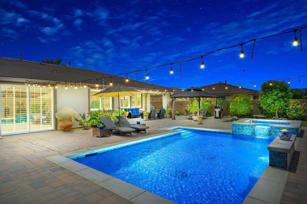 Located in the highly sought-after GATED COMMUNITY of Generations, this beautifully upgraded 4-BEDROOM, 3-bath home offers 2,188 sq. ft. of stylish, MOVE-IN READY living. The interior has been freshly painted, and features crown molding, tray ceilings, imported Italian porcelain marble-look tile in all bedroom and bathrooms, wood-tile floors in high-traffic areas, and wood shutters throughout. The REMODELED BATHROOMS have quartzite counters, refinished cabinets, upgraded fixtures, with the Primary Bath featuring glass vessel sinks and a rain shower head. The kitchen shines with a newer Samsung stainless steel 3-door refrigerator, decorative backsplash, and under-cabinet lighting. Other interior features include a built-in entertainment center, beautiful stacked-stone fireplace and custom built-in closet organizer at the Primary Bedroom. Outside is a true retreat: an oversized 25'x15' POOL & RAISED SPA, extended paver patio, large OUTDOOR GAZEBO with ceiling fan and privacy drapes, water features, mature yet low maintenance landscaping, overhead string lighting, and 40-year-old Saguaro cacti. Extras include an IQ security panel, 2 patio furniture sets, outdoor storage shed/containers, a pool vacuum, and more. A complete list of Features & Upgrades is available on this home. With LOW HOA DUES ($142/month), LOW TAX BASE w/NO MELLO ROOS, and close proximity to golf, shopping, schools and dining, this home offers a perfect blend of comfort, security, and outdoor living in one of the desert's most desirable neighborhoods.