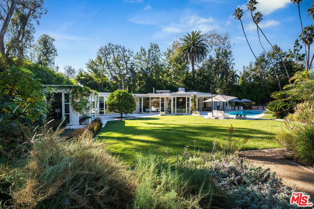 Nestled in the prestigious enclave of Lower Bel Air, 101 Bel Air Road offers a rare opportunity to own a meticulously reimagined, one-story estate on nearly an acre of lush, flat land. With approximately 4,731 sq. ft. of beautifully designed living space in the main house, this private, gated residence offers a serene retreat with exceptional indoor-outdoor flow, perfect for both elegant entertaining and relaxed living. The expansive lot offers approx. 39,751 sq. ft. of idyllic gardens with thriving grapevines, various fruit trees, plentiful gardens, winding paths, and manicured lawns, all enhanced by tranquil fountains and peaceful water features. A large motor court with ample parking adds convenience to this private oasis, while covered and open patios surround the property, offering countless places to enjoy the beautiful Southern California weather. The heart of the home is the sophisticated formal living room with a striking fireplace, providing a welcoming ambiance that flows seamlessly into the formal dining room. A modern gourmet kitchen is a true chef's delight, featuring professional-grade appliances, a large eat-in island, and high ceilings with a skylight to invite the warmth of morning sunlight. The kitchen opens into a spacious family room with its own fireplace, making the space ideal for both intimate gatherings and lively entertainment. The luxurious primary suite is a sanctuary of its own, complete with a cozy fireplace, a custom walk-in closet, a spa-like bathroom with premium finishes, and an adjoining office. For added comfort and convenience, the estate includes a fully equipped gym. The main house also offers two additional family or guest bedroom suites and a powder room. Additional structures on this property include a detached guesthouse offering two bedrooms and two bathrooms, perfect for visitors or as private workspaces. Additionally, a detached media and billiard room provides an exceptional setting for movie nights or game days. Designed for ultimate privacy and enjoyment, the outdoor spaces feature a sparkling pool, a rejuvenating spa, and a firepitperfect for year-round relaxation or entertaining under the stars. There is also a custom-built dog run at the back of the property to protect your precious pets. Originally built in 1947, the home has been thoughtfully updated to offer modern amenities while retaining its timeless charm. A true gem in one of Los Angeles' most coveted neighborhoods, 101 Bel Air Road offers the perfect balance of luxury, privacy, and tranquility.