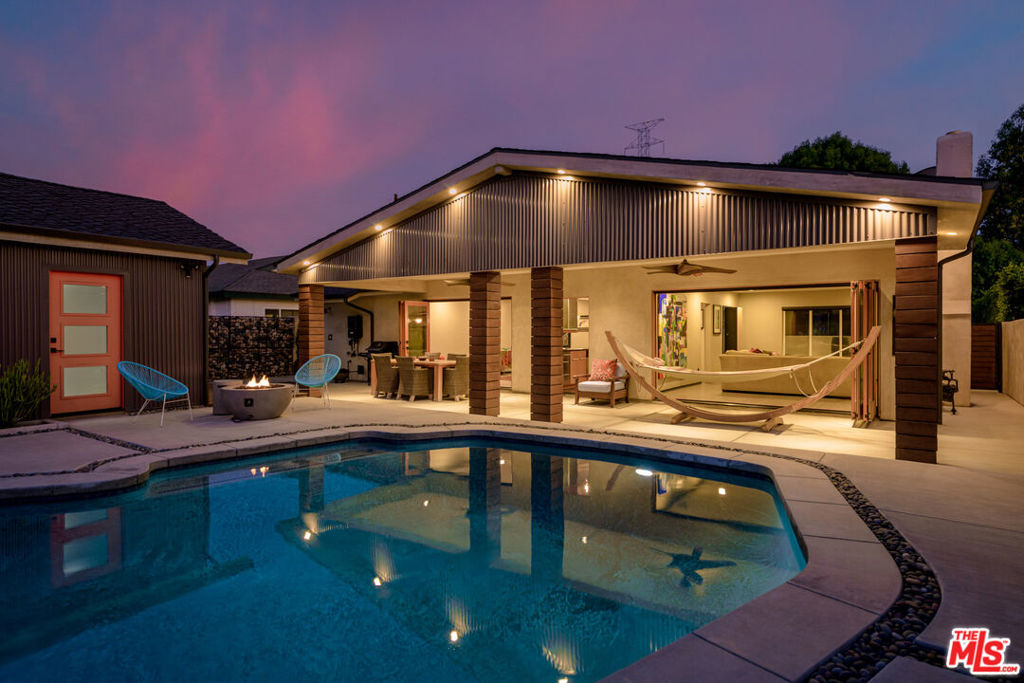 Welcome to The Azure Haus. Bespoke and beautifully renovated, this 3 bed / 2 bath home blends high-end design with thoughtful upgrades in a charming Valley locale. Featuring custom concrete walkways, serene water fountain, lush drought-tolerant landscaping and garden, Mexican river rock accents, and curated decking. The exterior includes smooth Santa Barbara stucco, an outdoor pool shower, custom accordion doors and pergola, iron gates, and Brazilian Ipe wood privacy fencing. Inside, enjoy real oak floors, South American porcelain tile, abundant natural light evoking an indoor-outdoor flow, and custom automatic blinds. The epicurean kitchen offers island seating, modern appliances, and open access to the formal dining room, with seamless transitions to al fresco dining by the pool. The primary suite boasts a spa-like bath with a Roman Jacuzzi tub, custom vanity, private outdoor seating, and stunning Missoni garden wallpaper. The backyard features a remodeled pool with Pentair system and an adjacent outdoor fire pit for relaxed evenings. The detached 2+ car garage, with epoxy floors and dual doors, offers ideal flex space for a gym, office, or creative studio. A true gem with exceptional private outdoor living, this home is a perfect combination of original architectural integrity and resort-style design. Close to The Vineyards at Porter Ranch, Fashion Center shopping, dining, entertainment, fitness, and local award-winning schools.