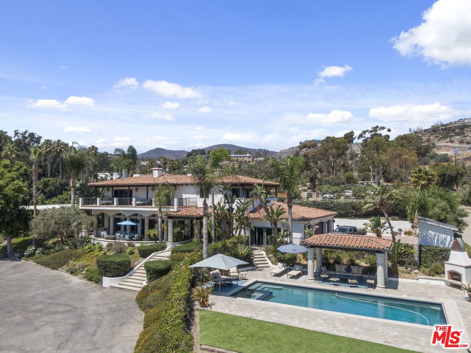 Welcome to Malibu Vista Ranch! Your Coastal Equestrian Dream Home! Just 100 yards from the beach and coastal access. This rare and expansive equestrian estate offers breathtaking ocean views and an unparalleled lifestyle. Nestled in one of Malibu's most sought-after locations, this property checks every box. The main residence features 4 spacious bedrooms and 5 beautifully appointed bathrooms. Step into the grand foyer with soaring ceilings and elegant Canterra stone pavers underfoot. The chef's kitchen is both functional and stylish, boasting top-of-the-line appliances, a large center island, a breakfast nook, and views of the ocean, lush yard and stables. With 11-foot ceilings and custom Canterra pillars, the living and family rooms exude luxury and open seamlessly onto a generous ocean-view patio ideal for entertaining or relaxing in style. Upstairs, the primary suite is a serene retreat with stunning ocean views, a custom fireplace, dual walk-in closets, a spa-like tub, and a spacious covered balcony. Three additional sunlit bedrooms also feature ocean views and their own large, covered balconies that extend the living space outdoors. Downstairs, the cabana lounge leads directly to the resort-style pool and spa area, complete with a fireplace and expansive outdoor entertaining space. Parking is abundant, with a motor court and a three-car garage. The charming ocean-view guest house offers two bedrooms, two bathrooms, a wrap around patio, private grassy yard, laundry room, and dedicated parking-perfect for visitors or extended family. Equestrian facilities are professionally designed for training or leisure and include Barn Master matted box stalls (some with in-and-outs), a tack room, office, grooming and bathing stations, a round pen, a ~200' x 150' riding arena with premium geo-textile footing. Whether you're riding horses, hiking or biking nearby trails, enjoying the beach, or exploring local shops and restaurants, Malibu Vista Ranch offers the ultimate coastal lifestyle just steps from the sand and with panoramic ocean views.