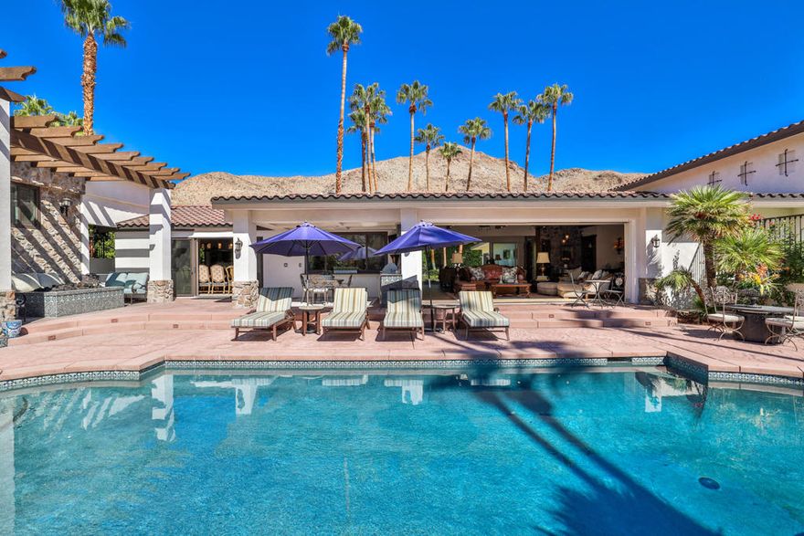 Casa Suenos - An Architectural Masterpiece in South Palm Springs.Tucked away in the exclusive enclave of Andreas Hills, Casa Suenos is a private sanctuary where timeless elegance meets elevated design. Surrounded by mountains, the estate is bathed in sunshine, sheltered from the wind, and framed by awe-inspiring 360 views. This remarkable location offers the ultimate setting for enjoying the Palm Springs lifestyle, just moments from world-class hiking, premier golf, and vibrant downtown dining and shopping.Reimagined and completely rebuilt just three years ago, this 5,417 sq. ft. custom estate is a meticulously curated Spanish Colonial masterpiece infused with romantic Moroccan and French influences. Every finish, texture, and detail has been intentionally selected to create a cohesive vision of escape, romance, and refined beauty.Designed as your own personal resort, the property features a sparkling pool with cascading waterfall, tranquil fountains, citrus gardens, and multiple lounge areas set against dramatic mountain vistas. Pocketing sliding doors create seamless indoor-outdoor living, opening to a spectacular front-loaded pool and spa, a Spanish-tiled outdoor fireplace, a fully equipped al fresco kitchen, and a raised patio that captures what may be the most breathtaking mountain views in the entire Coachella Valley.The estate offers 4 luxurious en suite bedrooms plus a fully appointed detached casita with its own kitchen, living room, and laundry, perfect for extended family, guests, or private retreats. Grand living spaces are anchored by soaring vaulted wood-beamed ceilings, artisan tilework, bespoke cabinetry, and a handcrafted dark wood tequila bar--hallmarks of true craftsmanship.Blending elegance with comfort, the primary suite offers a romantic escape infused with warmth and style, complete with a spa-like bath, dual walk-in closets, and a private office for quiet retreat or stylish remote work. Each guest suite has been thoughtfully designed with en suite baths and elevated finishes to welcome visitors with the most refined taste.Casa Suenos is more than a residence, it's a timeless expression of romance and elegance, seamlessly intertwined with the sophistication of Palm Springs living.Welcome home to Casa Suenos.