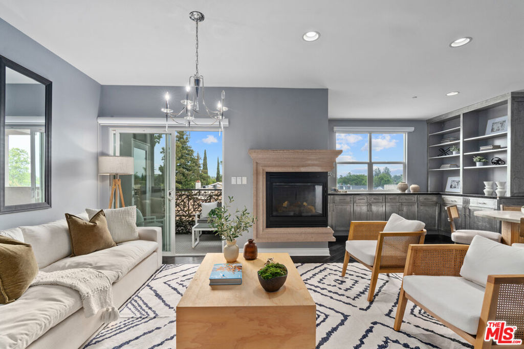 This stunning corner penthouse offers an exceptional blend of elegance, comfort, and convenience in one of Studio City's most desirable locations. Nestled on the top floor, this beautifully designed home welcomes you with a formal entryway leading into an expansive open living area, complete with recessed lighting, a cozy corner fireplace, and custom built-ins. The spacious dining area extends onto a private balcony, perfect for enjoying city views. Designed for both function and style, the gourmet kitchen features sleek stainless steel appliances, pristine stone countertops, and a breakfast bar ideal for casual dining or entertaining. A rare third bathroom adds an extra layer of luxury to this unique floor plan. The primary suite is a true retreat, boasting a massive walk-in closet, serene treetop views, and its own private balcony. The spa-inspired en-suite bathroom includes dual vanities, an oversized soaking tub, and a glass-enclosed shower. The spacious second bedroom offers tons of natural light and generous closet space making it an ideal guest suite or home office. Additional highlights include in-unit laundry, hardwood floors throughout the main living spaces, plush carpeting in the bedrooms, and recessed lighting in every room. This residence also includes two individual parking spaces and access to many guest parking spots. Lumiere is an impeccably maintained, boutique-style building featuring a beautifully landscaped central courtyard with a fountain and outdoor fireplace. Residents also enjoy a fully equipped gym on the first floor. Situated in a highly walkable neighborhood, this home is just two blocks from Beeman Park and within close proximity to top-tier restaurants, shops, and entertainment. This is a rare opportunity to experience luxury living in one of Studio City's most sought-after buildings.