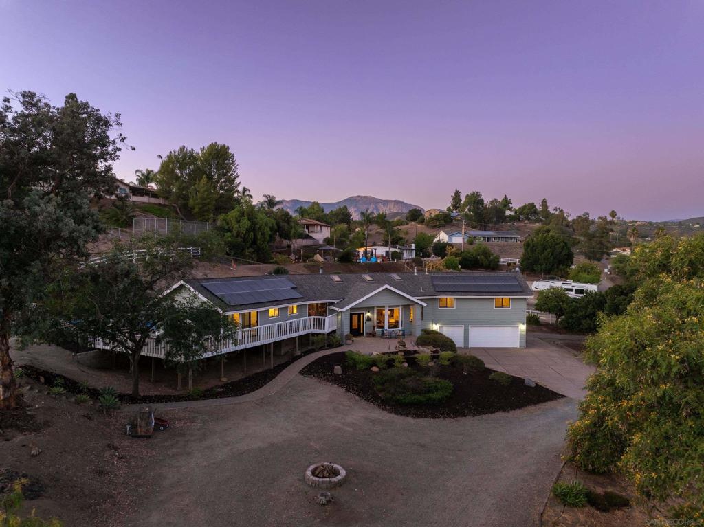 Discover The Ohana Ranch — a stunning countryside retreat set on 1.5 acres in scenic Blossom Valley. This 4-bedroom, 4-bathroom home offers 2,838 square feet of rustic elegance and modern comfort, set on a picturesque parcel with sweeping mountain views. Inside, vaulted ceilings with exposed beams and tongue-and-groove detail create a warm, open feel. Skylights and large windows fill the space with natural light. Travertine flooring runs through the main living areas, with durable laminate in the rest of the home. Custom chandeliers, a gas fireplace, and built-in bar complete the inviting interior. The chef’s kitchen includes a granite island, refinished cabinetry, stainless steel appliances, and a bay window framing the mountain backdrop. The well-planned layout includes a private primary suite tucked into its own wing complete with a view deck for sunset watching. Outside, relax in a resort-style setting with a pool, waterfall, jacuzzi, and paver patio surrounded by mature landscaping and citrus trees. Horse facilities include a four-stall barn with water and electricity, lunging arena, and shaded paddock. The barn sits on a permitted foundation designed for a future home, offering ADU or guest house potential. Extras include a Tesla charger, three-car garage with storage, owned solar, dual-zone HVAC, custom window treatments, and stamped concrete drive. The Ohana Ranch is a rare chance to enjoy peaceful ranch living with luxury and room to grow.