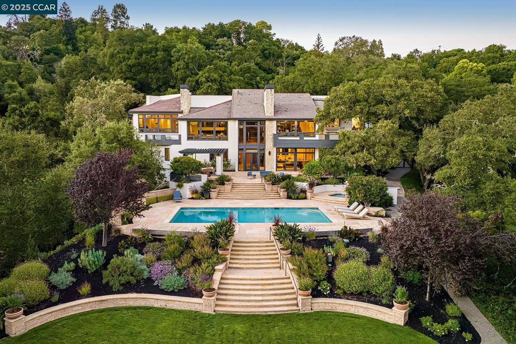 Ultimate privacy in every direction, as 7 acres of surprisingly low-maintenance landscaping provide seclusion and inspiring nature views. Situated on a knoll graced with huge oak trees, this home’s only owner was a prominent local builder. Featuring nearly 10,000 SF of custom living space, it’s comfortable for everyday living but designed for entertaining on a grand scale in the wide-open foyer, living and family rooms with wet bar. On the entry level, the primary suite consists of a huge bedroom, adjoining office/gym, and an en-suite bath with spa tub and shower, and dual sinks, water closets and walk-in closets. Also on the main level are the dining room which easily seats 12, the kitchen and breakfast nook, both with treehouse views and nearby access to the 4-car garage. Light-filled with picture windows, this home sets up perfectly for multi-generational living, with a studio under the garage, and the mid-level bedroom both with direct exterior access. Lower-level bedrooms are en-suite, and everyone will enjoy the recreation room, which has a wet bar and room for gaming. The adjacent full bath, which also has a sauna and steam shower, serves the huge stone deck patio, swimming pool and spa, and grass play area. Tennis court easily converted to pickleball. Extensive storage.