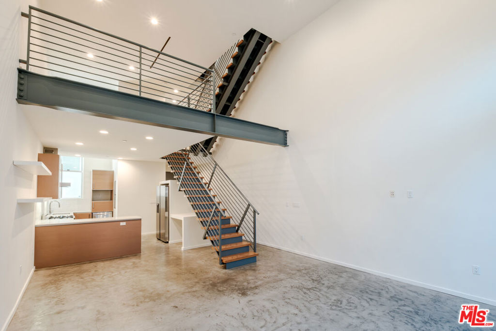Offered Unfurnished and Available for Immediate Occupancy! Warm architectural character meets modern industrial design in this striking 2-bedroom + loft, 2.5-bath residence in the highly sought-after Art Lofts of West Hollywood. Spanning approximately 1,830 sq ft across four light-filled levels, this townhouse-style condo features soaring 20-foot ceilings, dramatic Fleetwood windows, and a seamless blend of polished concrete and hardwood flooring. The flexible floor plan includes a spacious loft ideal for a home office, creative studio, or media lounge. A sleek chef's kitchen with stainless steel appliances anchors the main living area, flowing effortlessly into open concept living and dining spaces perfect for entertaining. Enjoy seamless indoor-outdoor flow with a private balcony off the living room and a spacious rooftop patio capturing tranquil views of the surrounding hills. Additional highlights include generous closet space, in-unit laundry, and two-car tandem parking with private storage. Set within a gated 12-unit community with guest parking and an onsite spa, and located just minutes from Whole Foods, Sunset and Santa Monica Boulevards, premier gyms, restaurants, and cafes this residence offers an exceptional fusion of architectural style and urban convenience.