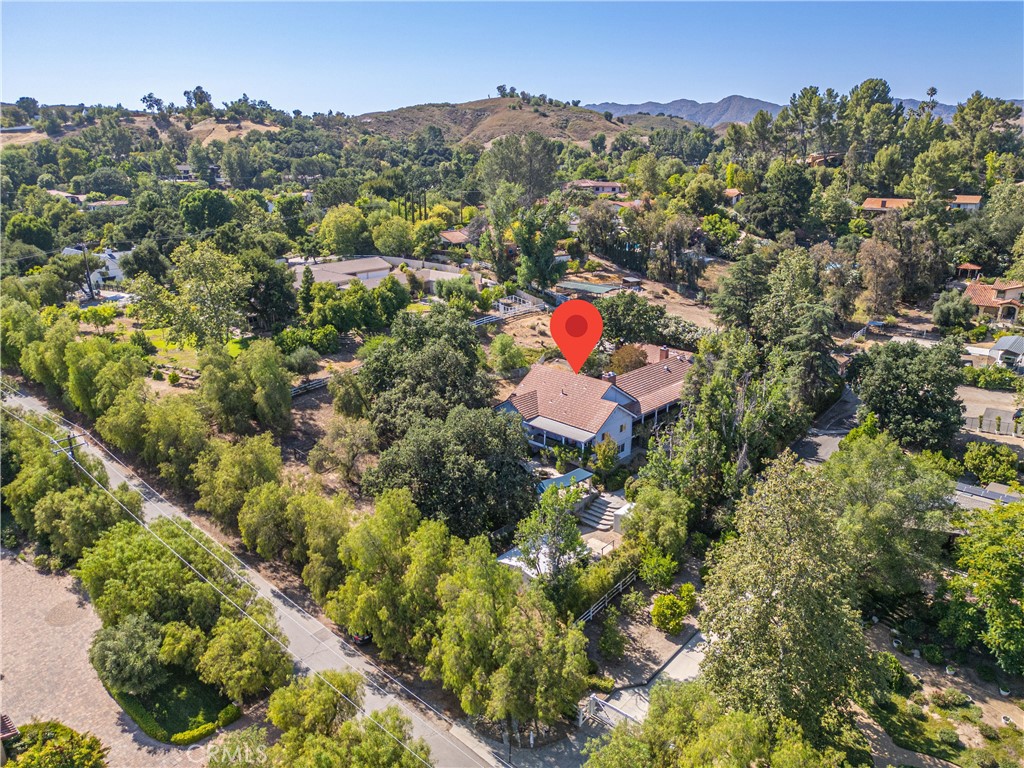 A Private Gated Celebrity-Owned Sanctuary Where Elegance Meets Nature. “La Bijou Cache” The Hidden Jewel. Step into a world of timeless beauty and tranquility on this exceptional 1.25-acre equestrian estate in Old Agoura offering 225 foot gated frontage on Balkins Drive and main gated entrance along a long paver driveway on Colodny Drive. This 5 bed, 5 bath 4244 square foot haven plus 3-car garage is masterfully curated with soul, style, and sophistication. This is more than a home; it’s a lifestyle retreat designed to inspire and restore. From the moment you enter, you’re welcomed by vaulted ceilings, rich textures, and a feeling of serene grandeur. Outside, meander thru tranquil pathways past a koi pond with cascading waterfall, or gather around the fireplace and fire pit in the dedicated outdoor crescent-shaped lounge under the stars. The secluded waterfall pool, spa and covered pergola promise peaceful relaxation or entertaining. Wraparound porches and French doors encompass all entertaining rooms abundantly embracing the home, blurring the line between indoor and outdoor living. Inside, a Parisian style “Moulin Rouge” inspired formal living room. Grand 2-story billiard room with 1 of 3 indoor fireplaces. The family-style chef’s kitchen with 2nd fireplace and high vaulted ceilings features a show-stopping La Cornue range and invites culinary passion. The primary suite is pure indulgence with floor-to-ceiling fireplace, retreat area, private covered porch, custom fitted walk-in closet and opulent European-inspired bath adorned in Venetian plaster. For those who desire a large home/work space with separate entrances, look no further. One level houses the separate 5th bed & 3/4 bath guest suite with private entrance and large covered patio; ideal as optional rental income possibility or for caretaker, groundskeeper, etc and is adjacent and attached to the multi-purpose room which currently serves as a media room, pilates and music studio-Ideal for creatives, musicians, fitness trainers, or any work/live business environment. For equestrian enthusiasts, the 2-stall barn and tack room open directly to a spacious turnout and shaded pasture offering the rare blend of luxury and country charm. This estate is a rare jewel-private, poetic, and impossible to replicate. Showings are limited and demand is high. Don’t wait-schedule your private tour now and experience the magic for yourself.