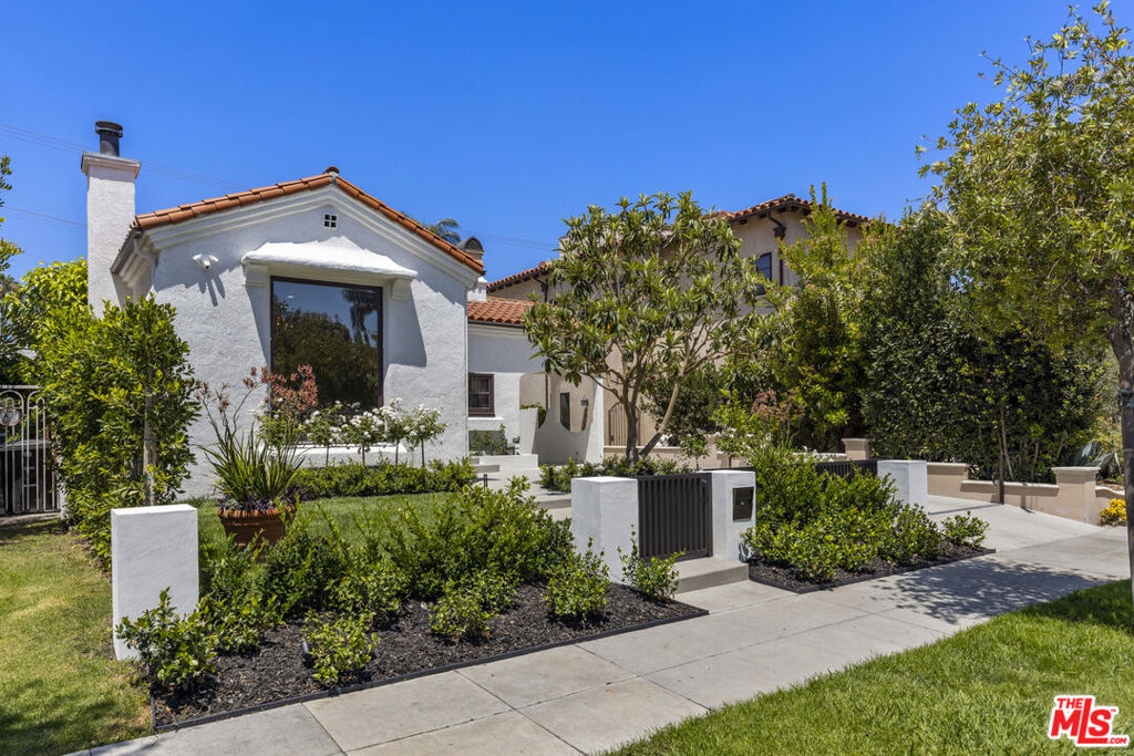 Presenting a beautiful, freshly updated 1930s Spanish at the edge of Beverly Grove in a prime location and one of the best pockets of the city. Set behind a secure, gated entry with manicured landscaping, a grassy lawn, and blossoming florals, the home's charming facade welcomes guests inside. Discover a bright and elegant formal living room with large picture window, stylish original details throughout, traditional mouldings, stucco wood-burning fireplace, wide-plank oak floors, and farmhouse-style casement windows. Chandeliers and light fixtures are elegant. Adjacent to the formal dining room is the gourmet kitchen, complete with garden window, large stone-topped center island, custom cabinetry, backsplash, and top-tier appliances. Stackable laundry with wash sink is nearby. Bedrooms are spacious, and bathrooms are appointed with on-trend cabinetry and hardware, with a smart mirror and dual-sink vanity in the main bath. There is also a bonus room/home office, ideal for remote work or creative use! The rear patio/outdoor living area is the perfect place to relax, entertain, barbecue, and dine al-fresco below enchanting string lights on warm summer evenings. The gated front yard has a long, private driveway, garage, and porte-cochere offering ample parking for multiple cars. Welcome to this highly sought Beverly Hills location central to museums, parks, fine dining, and nightlife, just moments to top Beverly Hills amenities, the Westfield Century City mall, the Beverly Center, Cedars-Sinai, Trader Joe's, Rodeo Drive, The Grove and Original Farmers Market, and all the very best of the Westside. Some photos are virtually staged.