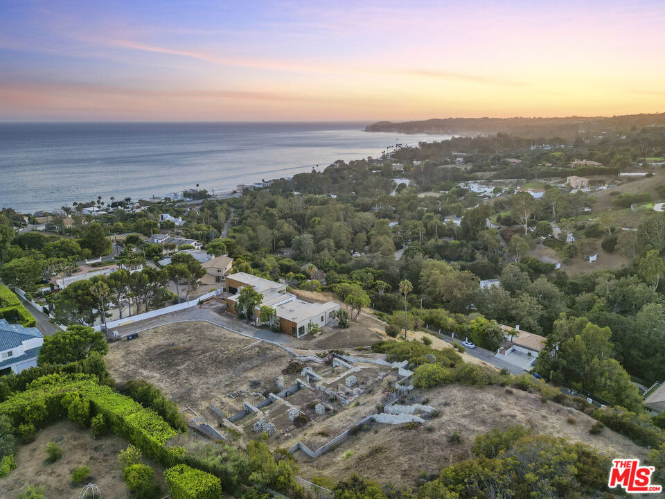 A rare 4.3-acre whitewater ocean view estate site with an approved Coastal Development Permit and proposed plans by distinguished Los Angeles modernist architect John Dutton, AIA. Perfectly situated on Sea Vista Drive, combining two contiguous lots in Sycamore Park, one of Malibu's most coveted private enclaves, this property offers the unique opportunity to create a 6,350-square-foot architectural residence with complete landscaping plans. Positioned at the end of a quiet cul-de-sac, the site backs onto miles of pristine state parkland, ensuring unmatched privacy, unobstructed natural beauty, and breathtaking vistas that stretch from sunrise over the Santa Monica Mountains to sunset over the Pacific, with sweeping views from Point Dume to the horizon. The proposed residence is thoughtfully designed to blend seamlessly into the hillside, with three levels stepping gracefully up the terrain. A private elevator connects all floors, including a three-car garage with generous storage. The first floor features a welcoming entry, open living and dining areas, a gourmet kitchen, guest bedrooms, and a seamless flow to the pool and outdoor dining terraces. The second floor is dedicated to the primary suite with an oversized deck, along with flexible space for one to two additional bedrooms or a studio. In total, the home offers the possibility of up to six bedrooms and four and a half baths, with the current design allowing for versatile four- to six-bedroom configurations. The landscaping plan showcases a native, drought-tolerant palette designed to complement the natural canyon and coastal environment. Layered terraces with ocean-view gardens, stone pathways, and shaded seating areas surround an infinity-edge pool framed by lush greenery and dramatic coastal backdrops. Integrated lighting and irrigation systems provide year-round beauty and ease of maintenance. Lifestyle amenities abound, with residents enjoying golf cart access to the private Sycamore Park Tennis Club or through the exclusive tunnel under Pacific Coast Highway that leads directly to the beach. The property also offers direct access to hiking trails, including the famed Escondido Falls, and is just minutes from Malibu's dining, shops, cultural attractions, and schools such as Pepperdine University, the new Santa Monica College satellite campus, and renowned destinations including Nobu and Soho House. This is a unique opportunity to create an extraordinary modern estate in one of Malibu's most desirable locations, with architecture, landscaping, and approvals already in place. A truly rare offering not to be missed, with years of work done and hundreds of thousands of dollars already invested in entitlements. Sale includes 2 lots, consisting of APNs: 4460-010-013 and 4460-013-001. Co-listed.