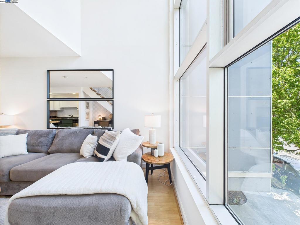 Soaring ceilings, iconic modern design, & an enviable Temescal address come together in this sun-splashed 1BD/1BA loft-style condominium. Tucked inside a boutique building, Unit 201 is a bright and airy corner unit with dramatic floor-to-ceiling windows that flood the space with natural light and lush treetop views. The open-plan layout offers a fluid blend of living, dining, and entertaining space. A sleek kitchen anchors the main level with two-tone shaker cabinetry, stainless steel appliances, and granite countertops. The voluminous living area seamlessly connects to a cleverly tucked-away home office nook beneath floating wood stairs—an ideal remote-work setup. The modern bath is crisp and calming with a granite vanity, tiled shower-over-tub, and contemporary tiling. Upstairs, the spacious loft bedroom features serene leafy views, plush carpeting, a full-sized laundry closet with stacked washer/dryer, and room to relax or create. this home puts you in the vibrant heart of Temescal—just blocks from buzzing Temescal Alley, cult-favorite spots like Bakesale Betty, Pizzaiolo, as well as trendy eateries like Tacos Oscar, Teni East, Cholita Linda, award recognized spots like Burdell. Whole Foods is just a few minutes drive away. MacArthur BART is down the street!