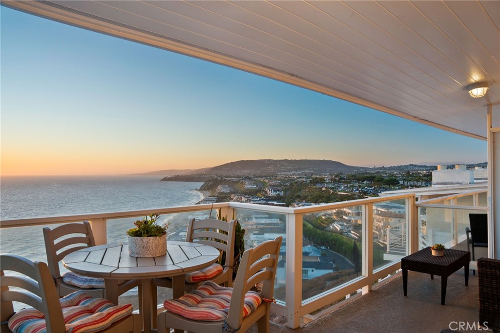 Perched above one of Southern California’s most coveted stretches of coastline, this exceptional two-bedroom, two-bath residence commands an unrivaled setting along the bluffs of Dana Strand Road. Just steps from Strands Beach and bordering The Strand at Headlands, Dana Point’s premier oceanfront enclave, the home offers sweeping, unobstructed 180-degree views that encompass Catalina Island, Palos Verdes, dramatic white-water coastline, rolling hills, city lights, and even Saddleback Mountain in the distance. Completely reimagined and taken down to the studs in 2015, this top-floor condominium blends timeless craftsmanship with modern sophistication. Inside, soaring cedar ceilings crown an open-concept layout where living, dining, and kitchen spaces flow seamlessly. Expansive glass doors frame endless ocean vistas and open to a private balcony with sleek glass railings, creating a perfect setting for enjoying sunsets, sea breezes, and the soothing sound of waves. The primary suite is a serene retreat, appointed with custom built-ins, a dedicated work space, and a spa-inspired bath. Its private balcony, finished with limestone flooring and a pergola, captures tranquil views of the coastal reserve and glittering city lights. Throughout, the home showcases refined finishes including porcelain tile flooring, recessed lighting, solid-core doors, insulated walls, and a striking stone fireplace that anchors the living space. Additional highlights include skylights, a tankless water heater, an upgraded furnace, and the convenience of both a private garage and driveway parking. Beyond the home itself, the location is unparalleled. Elevated above more than a mile and a half of protected shoreline and 70 acres of preserved natural space, residents enjoy direct access to scenic parks, coastal trails, and Dana Point’s vibrant lifestyle. World-class golf, luxury resorts, fine dining, yachting, and entertainment are just minutes away—yet at home, each day feels like a private coastal sanctuary where the beauty of the sea is always at your doorstep. This exceptional property is also set to benefit from the exciting Dana Point Harbor revitalization project.
