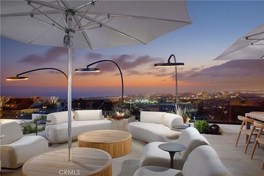 Perched atop Spyglass Hill with sweeping views of the Pacific, Catalina Island, Newport Harbor, and glittering city lights, this newly reimagined coastal estate offers rare serenity just minutes from Fashion Island and Corona del Mar Village. Marrying warm contemporary design with refined craftsmanship, the home embodies the best of elevated Southern California living. Beyond a stately teak-gated entrance, a cobblestone drive winds through manicured gardens to reveal a striking façade of smooth plaster and expansive picture windows—a prelude to the exquisite interiors. At the center, an open-air Mediterranean-modern courtyard invites starlit gatherings around a sculptural fire feature, seamlessly blurring the line between indoor and outdoor living. Designed for both grand entertaining and intimate living, the estate features two fully equipped kitchens. The primary chef’s kitchen includes a 72” AGA Induction range, Sub-Zero glass-panel refrigeration, Miele espresso system, dual dishwashers, and Wolf microwave. Calacatta Terrazzo, Naval Brass, rift white oak cabinetry, and Dorn Bracht fixtures elevate every detail. The adjoining catering kitchen adds a 48” Viking Pro gas range, under-counter refrigeration, warming drawers, and passthrough service for effortless hosting. The open-concept great room connects dining, living, and outdoor spaces with a Bang & Olufsen sound system and floor-to-ceiling glass that opens to a sun-drenched terrace. Outside, enjoy a heated pool and spa, curated gardens, al fresco dining, and lounge areas with unforgettable views. Private quarters are equally refined. Two primary suites offer panoramic ocean-to-mountain vistas, spa-caliber baths finished in Pink Cristallo quartzite, Fantini fixtures, in-suite laundry, walk-in closets, and LG clothing steamers. Two additional guest suites provide quiet luxury and comfort. An executive office with custom built-ins anchors the main level, while a second office-library in the primary wing opens to fresh air and natural light. A hidden media experience, wet bar, two powder rooms, and a beautifully appointed laundry room with pet wash enhance day-to-day living. Throughout the home, handcrafted Moroccan Zellige tile adds texture and quiet sophistication. A hidden speakeasy—discreet and inviting—offers the perfect setting for rare spirits and private evenings. This is not merely a remodel, but a masterful reinvention—crafted for those who value design, distinction, and the art of living well.