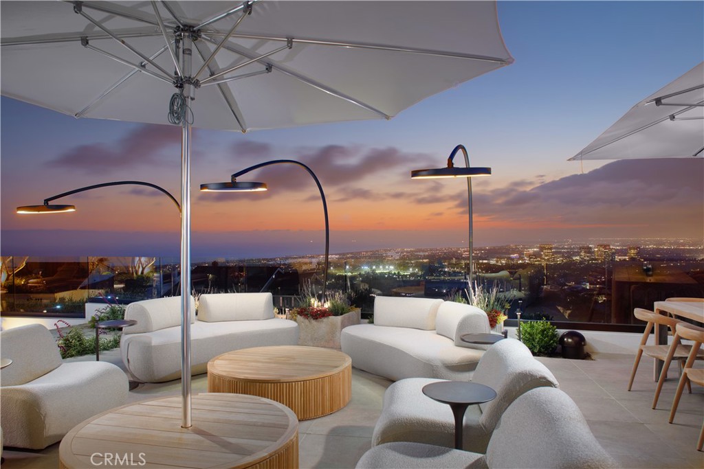 Perched atop Spyglass Hill with sweeping views of the Pacific, Catalina Island, Newport Harbor, and glittering city lights, this newly reimagined coastal estate offers rare serenity just minutes from Fashion Island and Corona del Mar Village. Marrying warm contemporary design with refined craftsmanship, the home embodies the best of elevated Southern California living. Beyond a stately teak-gated entrance, a cobblestone drive winds through manicured gardens to reveal a striking façade of smooth plaster and expansive picture windows—a prelude to the exquisite interiors. At the center, an open-air Mediterranean-modern courtyard invites starlit gatherings around a sculptural fire feature, seamlessly blurring the line between indoor and outdoor living. Designed for both grand entertaining and intimate living, the estate features two fully equipped kitchens. The primary chef’s kitchen includes a 72” AGA Induction range, Sub-Zero glass-panel refrigeration, Miele espresso system, dual dishwashers, and Wolf microwave. Calacatta Terrazzo, Naval Brass, rift white oak cabinetry, and Dorn Bracht fixtures elevate every detail. The adjoining catering kitchen adds a 48” Viking Pro gas range, under-counter refrigeration, warming drawers, and passthrough service for effortless hosting. The open-concept great room connects dining, living, and outdoor spaces with a Bang & Olufsen sound system and floor-to-ceiling glass that opens to a sun-drenched terrace. Outside, enjoy a heated pool and spa, curated gardens, al fresco dining, and lounge areas with unforgettable views. Private quarters are equally refined. Two primary suites offer panoramic ocean-to-mountain vistas, spa-caliber baths finished in Pink Cristallo quartzite, Fantini fixtures, in-suite laundry, walk-in closets, and LG clothing steamers. Two additional guest suites provide quiet luxury and comfort. An executive office with custom built-ins anchors the main level, while a second office-library in the primary wing opens to fresh air and natural light. A hidden media experience, wet bar, two powder rooms, and a beautifully appointed laundry room with pet wash enhance day-to-day living. Throughout the home, handcrafted Moroccan Zellige tile adds texture and quiet sophistication. A hidden speakeasy—discreet and inviting—offers the perfect setting for rare spirits and private evenings. This is not merely a remodel, but a masterful reinvention—crafted for those who value design, distinction, and the art of living well.