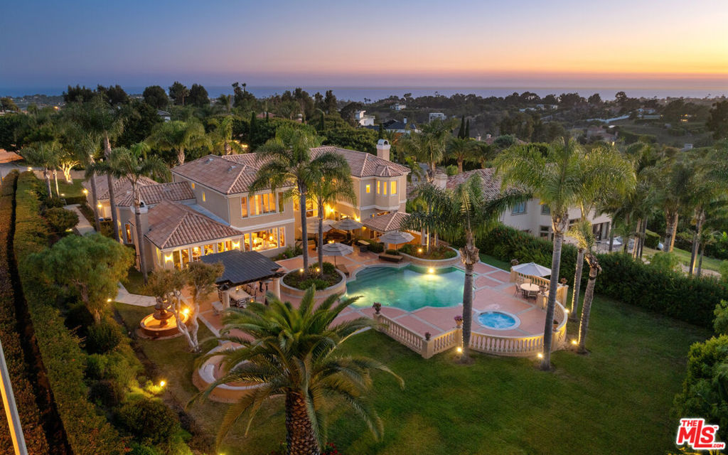 Welcome to this extraordinary estate, where timeless elegance meets modern luxury. Every detail of this expansive home has been thoughtfully designed to offer a sophisticated and comfortable living experience. A grand foyer sets the tone with a dramatic chandelier and soaring two-story ceilings over rich wood floors. Step down into the formal living room with stone tile floors, wood beams, blackout curtains, and a gas fireplace. French doors lead to a covered patio with a chandelier and built-in heaters, perfect for indoor-outdoor living.A stylish powder room features stone counters, fine art lamps, and an elegant vanity. The formal dining room offers a chandelier, pool views, French doors to the backyard, and a bar with built-insideal for entertaining. The gourmet kitchen is a chef's dream, complete with a butler's pantry, unpolished granite counters, stone tile floors, Sub-Zero fridge/freezer, Bosch 5-burner range and oven, microwave, wine cellar, wine fridge, trash compactor, Bosch dishwasher, and abundant storage including a walk-in pantry. The sunny breakfast area features high coffered ceilings and warm wood flooring.The adjacent living room is inviting and light-filled, with vaulted beamed ceilings, a gas fireplace with a large mantle, built-in cabinets, and French doors to the backyard. A piano may remain with the home, if desired. On the main level, a large guest suite functions as a secondary primary bedroom, with wood-beamed ceilings, stone tile floors, French doors, and an en-suite bath featuring a jetted tub, shower, dual sinks, vanity, and a spacious closet. A nearby hallway with closet space leads to another bedroom with wood floors and an en-suite bath. A large laundry room with washer/dryer, built-ins, sink, and French windows sits at the end of the hall, near a three-car garage with built-in storage. Upstairs, one bedroom offers wood floors, high ceilings, pool and mountain views, and an en-suite bath with stone counters, a shower-over-tub, and a custom closet. Another bedroom has wood floors, ocean views, French doors to a balcony, and a full en-suite bath with built-ins.The expansive owner's suite is a true sanctuary, with French doors, wood floors, a stone fireplace, Juliet balconies, high ceilings, ocean views, and space for a sitting area. The suite includes a custom walk-in closet with built-ins, glass and wood cabinetry, and a center island. The spa-like bath features ocean views, a jetted tub, large shower with dual heads, makeup vanity, dual sinks, and two water closets one with a bidet.The resort-style backyard offers a private oasis with lush landscaping, mature trees, and privacy hedges. Highlights include a large pool with a waterfall, built-in jacuzzi, covered dining area with chandelier and retractable sun screens, a fire pit with bench seating, and elegant fountains. The front yard includes a large lawn, sprinkler system, pedestrian gate, and a circular driveway with space for eight cars.Additional features include three central AC units, alarm system pre-wiring, new water heaters, circulation pump, and extensive built-in storage throughout. This remarkable estate offers luxurious living at every turnready to welcome you home.