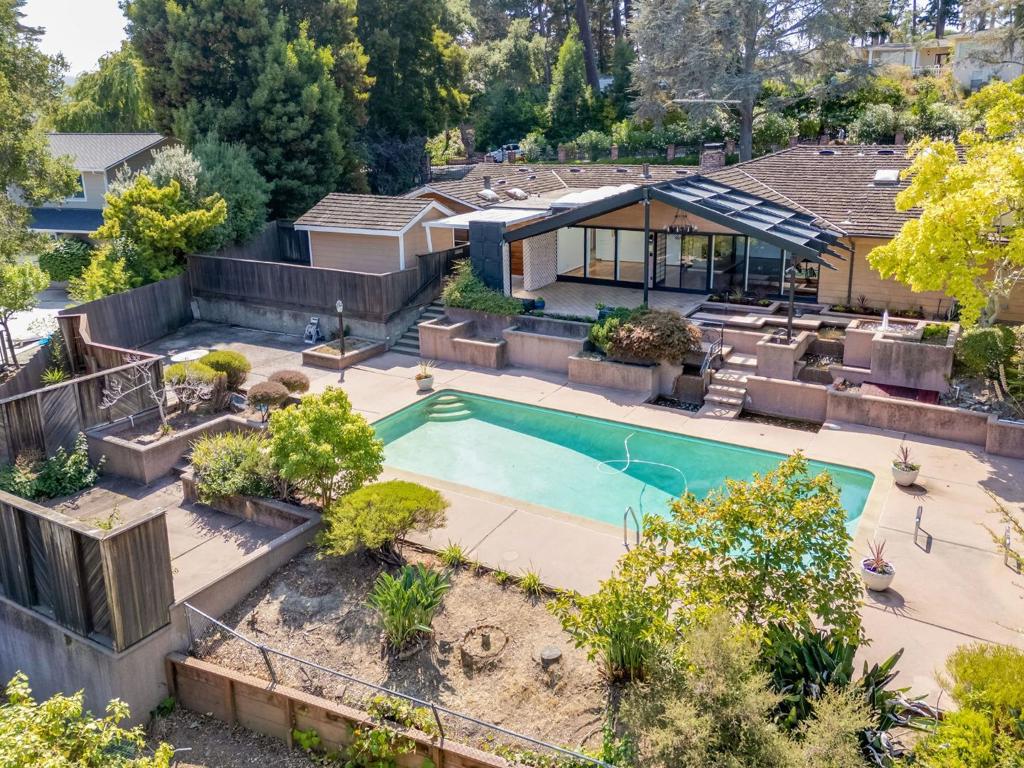 Situated in the prestigious Carolands, 530 Darrell Rd combines timeless character with modern convenience. With easy access to I-280, it offers equal commute times to San Francisco and Silicon Valley, lies within a top-rated school district, and is just 2.5 miles from Downtown Burlingame. Double wooden entry doors with custom leaded glass (sold separately) open to a bright living room with stone fireplace, wood-paneled ceiling, recessed lighting, and wall of glass to the covered lanai. The dining room, framed by Japanese-inspired sliding doors, is lit by skylights that reflect off hardwood floors. The eat-in kitchen has a breakfast nook, pantry, butler's pass-through, granite island with sink and bar, built-ins including dual ovens, cooktop with hood, paneled refrigerator, and a rare cooking fireplace. Off the kitchen are an en-suite guest room with outdoor access, maid's room, and garage. A bedroom/office and powder room complement the foyer, while the opposite wing hosts 3 bedrooms and 2 baths, including the primary suite with high ceilings, fireplace, patio, and spa-like bath. Outdoors enjoy a lanai with pond, fountains, waterfall, sparkling pool, patios, lawn, mature trees, outdoor powder, paver driveway, 2-car garage, and shed.