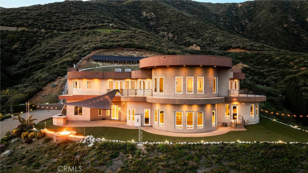 WELCOME TO 10320 SNOWDROP Rd, a beautiful estate located at the top of Rancho Cucamonga! The endless, panoramic views of the valleys and mountains are incomparable from this magnificent home. Designed with modern elegance, this home features soaring ceilings and expansive windows that flood every space with natural light.
The main floor boasts breathtaking views from nearly every space, including the central living room, game room with a wet bar, dining area with patio access, and family room featuring a stone hearth fireplace. Multiple patios on both sides provide serene outdoor retreats. The chef's kitchen features bamboo floors, custom cabinetry, granite countertops, a large island with a secondary sink, and stainless-steel appliances, including a dual-drawer dishwasher. A private main-level suite with a kitchenette offers flexibility as a guest suite, ADU, or office—ideal for multigenerational living.
Upstairs, a curved walkway with expansive windows leads to the luxurious primary suite featuring a retreat area, private balcony, oversized walk-in closet, spa-inspired bath with jetted tub, dual sinks, and a walk-in shower. Additional bedrooms include two en suites with private baths and walk-in closets (one with its own balcony), plus a fifth bedroom with hillside views.
A finished basement adds flexible space for a gym, music studio, wine cellar. The detached garage fits seven cars, with one bay currently serving as a workshop.
Additional Highlights:
Paid 29 KW ground-mounted solar system
Ground-level RV parking, gated driveway, and propane firepit
Outdoor cooking area
Four Bryant Evolution HVAC systems (5 zones)
Tankless water heater with recirculating pump
400-amp panel, surge protector, generator port, and EV charging
Central vacuum with in-wall hide-a-hose
Smart wiring throughout for data, audio, and video
This extraordinary estate offers luxury, flexibility, and breathtaking views—schedule your private tour today!