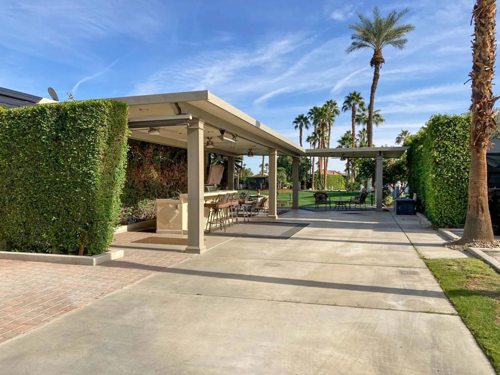 This exceptional luxury RV lot offers breathtaking east-facing views of the 6th Hole, a tranquil pond with an illuminated fountain, and a charming bridge, while the west-facing vistas encompass the putting green, driving range, tennis courts, and the main clubhouse. Privacy is ensured by lush ficus hedges, with unobstructed views both front and rear. Designed with convenience and comfort in mind, the lot provides ample parking for two vehicles and a golf cart, making it a perfect retreat for the discerning RV owner.The centerpiece is a stunning 644-square-foot insulated shade structure, featuring 16 dimmable nickel can lights, 4 remote-controlled fans with dimmable lights, 3 heaters, and a remote-controlled west sunshade. The fully equipped marble kitchen center includes a stainless steel sink with a hand wand and garbage disposal, a Kenmore mini refrigerator, a Vintage stainless steel gas BBQ, a dual cooktop, a dishwasher, and ample storage. Entertain in style with a 50″ Samsung Smart TV and elegant furnishings, including a glass dining table with swivel chairs, a loveseat, ottoman, coffee table, and area rugs. This lot is complete with reinstalled heaters and an electric water heater, offers the ultimate in luxury RV living. Owner financing is available with 50% down. Don't miss this rare opportunity to own a private, fully equipped lot in a premier location.Outdoor Resort Indio is a class-A only motorcoach community.