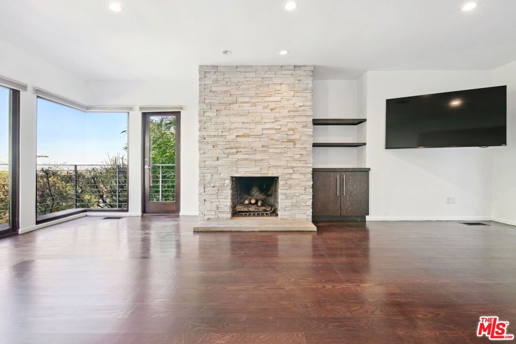 Nestled in an exceptional location just above the iconic Chateau Marmont and the vibrant Sunset Strip, this stunning 3-bedroom, 4-bathroom architectural retreat effortlessly combines elegance, comfort, and spectacular city views. Designed to make the most of space and natural light, the home's open floor plan seamlessly integrates indoor and outdoor living, creating an ideal environment for both entertaining and relaxing. As you step inside, you're welcomed by a formal entrance that flows into the spacious and inviting living area. An open layout, a cozy fireplace, and striking glass walls that frame breathtaking city views from Downtown LA to Century City, make it the perfect spot to unwind or host guests. Just off the living room, the outdoor space showcases a generously sized deck surrounded by lush greenery, offering a peaceful, private sanctuary. A cascading waterfall further enhances the tranquil atmosphere, seamlessly integrating indoor and outdoor living. A comfortable family area situated between the living and dining spaces effortlessly flows into the expansive kitchen - a true haven for cooking enthusiasts. Equipped with stainless steel appliances, sleek countertops, a breakfast bar, abundant workspace, and ample storage, the kitchen is designed to inspire your inner chef! The soaring 10-foot sky-lighted ceilings fill the space with natural light, and a unique balcony featuring a built-in barbecue invites you to enjoy grilling while taking in the mesmerizing city views below. Adjacent to the kitchen, the dining room offers versatility, with sliding pocket glass doors that can be opened for casual meals or closed to create an intimate setting for formal dining. The first level also features a convenient powder room, a spacious pantry, a well-appointed laundry area, and easy access to a serene outdoor space, perfect for al fresco dining or relaxation. On the second level, you'll find the first bedroom with an en suite bathroom and direct access to the outdoors. Upstairs, the primary suite offers a true retreat, complete with a cozy fireplace, breathtaking views, a walk-in closet, and an office nook. The en suite bathroom features dual sinks, a shower, and a separate tub for a relaxing soak. A third bedroom with an en suite bathroom and private balcony completes the upper level, offering another incredible space to unwind while enjoying views of the city. Additional highlights of this home include hardwood floors throughout, a Nest Thermostat for enhanced comfort and efficiency, a two-car garage, and a private hilltop overlook area that provides even more stunning panoramic views of the Los Angeles skyline. Every detail of this home has been thoughtfully crafted for both comfort and sophistication, providing a seamless blend of modern luxury and serene living. Perched in an exceptional location, it offers the perfect balance of tranquility and proximity to the excitement of West Hollywood's renowned shopping, dining, and entertainment. This residence is not just a home, it's a lifestyle!