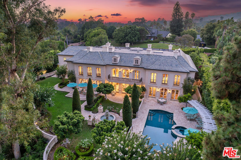 Sensational estate on stunning Saint Pierre Road, one of the most idyllic and iconic streets in prime lower Bel Air. Perfectly nestled just above famed Sunset Blvd through the East Gate, this extraordinary and awe inspiring two story traditional masterpiece leaves no detail spared with its epic custom finishes. With complete privacy throughout the sprawling grounds, the residence spans apx. 13,626 square feet on an apx. 35,282 square foot lot. Tucked behind two vehicle gates and one pedestrian gate, the front drive is expansive and leads to a luxurious 3 car garage. This prized showplace features 8 grand bedrooms, each with their own en suite bath, and an additional 4 bathrooms, Formal Living and Dining Rooms as well as a Game Room (complete with its own bar and wine cellar), Family Room, Breakfast Room and wood paneled Library. Enter the double front doors to find an Entry for the ages. With exquisite marble inlaid flooring, upholstered walls, a grand Calcutta staircase with custom iron detailing and a Rotunda, the entrance is nothing short of perfection. It has a direct view to the Formal Living Room, which boasts marble floors, paneled ceiling, and a trio of French doors overlooking the back terrace and babbling fountain. A true Chef's Kitchen brimming with architectural details has all the bells and whistles including a large island, Viking and Sub-Zero appliances, two dishwashers, double wall ovens, 2 refrigerators, 1 full height freezer, and 3 sinks in the Kitchen alone. A formal Butler's Pantry borders the Kitchen and has its own sink, custom cabinetry, and an abundance of upper and lower storage. The charming breakfast room with its wood parquet floors and built in cabinetry, has beautiful natural light and a lovely view to the backyard. The formal Dining Room is inspiring and robust with its very own fireplace. An elegant wood paneled Library sits off the main hallway and has its own bath and fireplace with a custom carved stone mantle. The impressive primary suite is highlighted by a magnificent balcony overlooking the majestic back landscape. Adjacent to the massive bedroom are separate dual bathrooms, one features impeccable marble detailing and a large soaking tub as a central focal point, the other features a sauna, and each feature sprawling closets and their own Sitting Room or Study, one with a kitchenette. In a separate private wing on the upper floor, you will find two staff bedrooms, a staircase leading downstairs, and a second Laundry Room. A chic elevator with paneled walls, stone flooring, and a brass ceiling light is perfect for accessibility. The impeccably curated grounds including a sparkling swimming pool, spa, built in BBQ with bar seating, meticulously manicured gardens, and multiple picturesque terraces, evoking the essence of a world class resort and offering an unparalleled experience in luxury and tranquility. Tucked away behind the exclusive Bel Air gates, this is a truly special offering in a most prestigious and spectacular location.