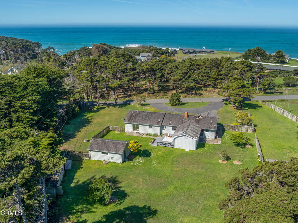 Whether you're seeking a serene primary residence by the sea or a high-performing vacation rental, this incredible mid-century modern, ranch-style home delivers. Just 200 feet from a private footpath to Hare Creek Beach, daily sunsets, coastal breezes, and the soothing rhythm of the ocean become part of your everyday experience.With projected short-term rental revenue exceeding $155k per year (AirDNA), this property presents a unique investment opportunity wrapped in timeless architectural charm. Set on over an acre, the 2,000 sq ft home offers 4 spacious bedrooms and 2.5 bathrooms. Towering native trees surround the property, creating a natural windbreak and private sanctuary for sunny afternoons and al fresco gatherings. The interior has been thoughtfully refreshed to blend classic style with coastal character--new flooring, interior paint, updated lighting, a remodeled bathroom, and tasteful improvements accentuate the original warmth of exposed wood built-ins and golden mid-century tones. The expansive primary suite offers a restful retreat, while the three additional bedrooms provide flexibility for family, guests, or office space. The original living room, anchored by a stunning flagstone fireplace, boasts large picture windows that frame unforgettable sunsets. An open-concept great room unites the kitchen, dining, and family room areas--perfect for entertaining. The kitchen bar seating connects seamlessly with the main living space, where oversized sliding glass doors lead to an expansive composite deck and wet bar--ideal for indoor-outdoor living.Additional features include a dedicated utility room, thoughtfully placed half-bath near outdoor access, abundant storage throughout, and multiple sliding glass doors that blur the line between indoors and out. Two separate single-car garages and additional outbuildings offer ample storage, while a circular paved driveway enhances ease of access and curb appeal.Located just south of city limits, this property offers rare privacy and convenience. Nearby attractions include local beaches, Mendocino Coast Botanical Gardens, hiking trails, surfing, mountain biking, and charming coastal towns--all within minutes. This is your chance to live, invest, and unwind along one of California's most picturesque coastlines.