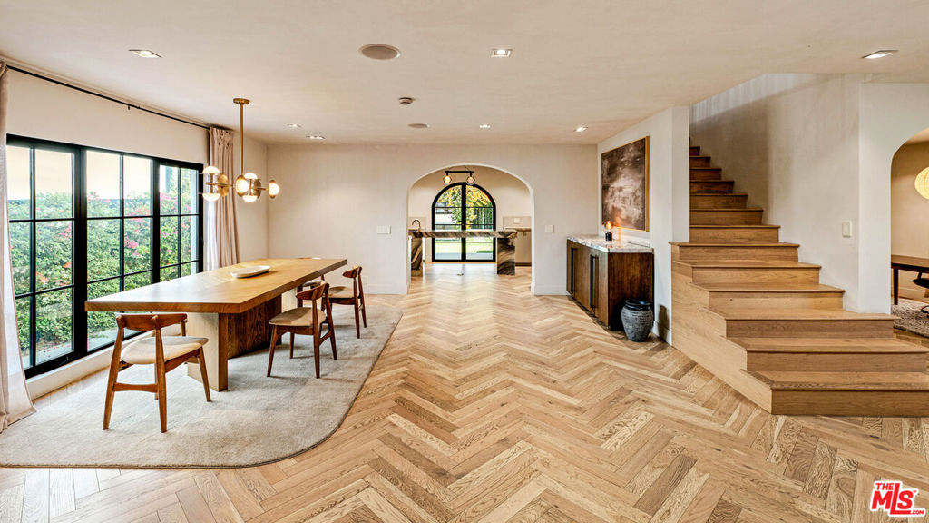 Welcome to this timeless 4-bed, 5-bath Spanish villa, just minutes from Hancock Park. Thoughtfully designed with plastered walls, graceful arches, and light-filled interiors, the home offers a seamless flow: a guest suite downstairs, three en-suite bedrooms upstairs, plus a versatile bonus room. The primary suite is a true retreat with a spa-like bath and oversized walk-in closet, while the chef's kitchen impresses with dual refrigerators, dual dishwashers, and top-tier appliances. Step outside to your private sanctuary complete with pool, spa, built-in BBQ, outdoor shower, fireplace, and TV perfect for effortless year-round entertaining. A fully integrated smart-home system puts everything at your fingertips, blending authentic Spanish charm with modern convenience in one of LA's most coveted locations.