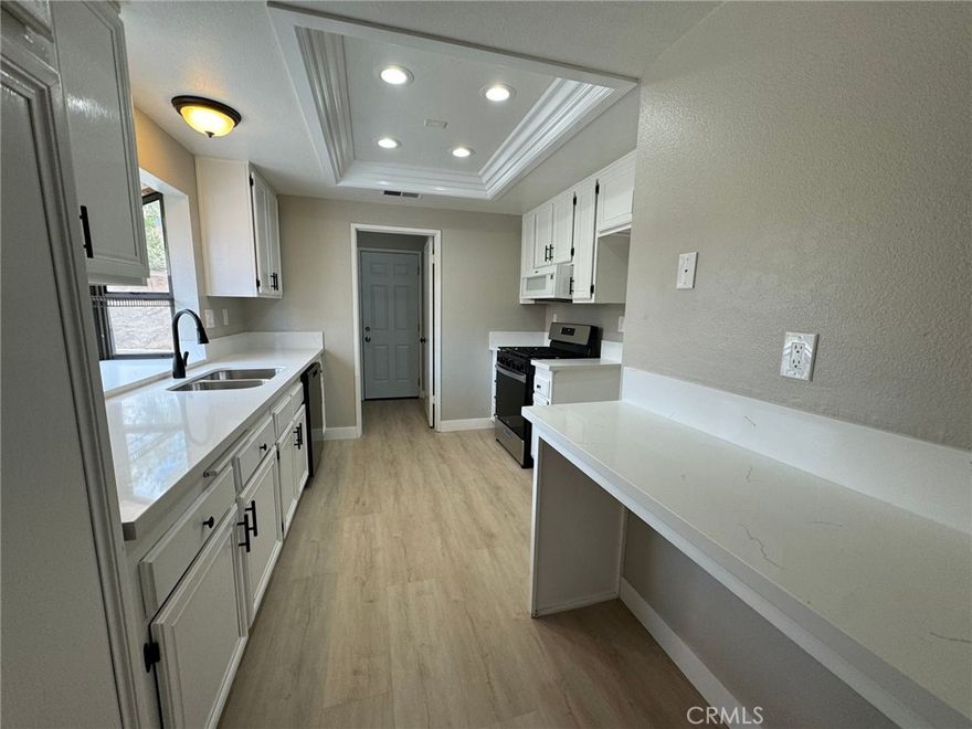 Welcome to this charming 2-bedroom, 2-bath home located in one of Menifee’s most desirable 55+ communities of Hacienda Hermosa—where comfort, convenience, and a relaxed lifestyle come together beautifully. As you enter, you’re greeted by a warm and inviting great room that blends the living and dining areas into one functional and open space. High ceilings, abundant natural light, and a seamless flow set the tone for easy living. The great room transitions effortlessly into the spacious galley-style kitchen, thoughtfully upgraded with brand-new quartz countertops, expansive prep areas, crisp white cabinetry, recessed lighting enhanced by crown-molding accents, and sleek black-and-stainless-steel appliances. A garden sink, breakfast bar, ample cabinet storage, and a large pantry provide everything you need for everyday cooking and entertaining. Just off the kitchen sits a convenient indoor laundry room with upper cabinetry for organization. The primary bedroom is a true retreat—generous in size and featuring a walk-in shower, dual sinks, a walk-in closet with designer shelving, and private back-patio access for enjoying your morning coffee or afternoon breezes. The secondary bedroom is well-appointed and ideal for guests or a home office. The guest bathroom offers wardrobe lighting and a tub-in-shower combination for added comfort.
Throughout the home, you’ll appreciate the stunning LVP flooring, neutral paint tones, raised baseboards, window coverings, ceiling fan, additional storage cabinets, and soaring ceilings that create an open, airy atmosphere. The fully finished 1.5-car garage is perfect for your vehicle, golf cart, or extra storage. Outdoors, a large covered patio offers the perfect setting for entertaining, relaxing, or enjoying the peaceful surroundings. The low-maintenance front yard and rare oversized backyard—fully fenced for privacy—provide endless opportunities to garden, host, or customize to your personal taste. There also appears to be potential for small boat parking along the side of the home. This delightful property offers comfort, style, and room to create the lifestyle you’ve been dreaming of. Don’t miss this wonderful opportunity!