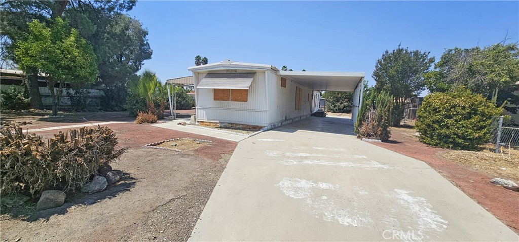 Discover the potential of this 2 bedroom, 2 bathroom manufactured home on owned land located in the City of Hemet. Nestled on a spacious 8276 square foot lot, a large carport sits to the right, and a screen room to the left ready for a fresh start. With a few repairs and a creative touch, it could transform into the ideal space for morning coffee, summer dinners, or a cozy lounge area perfect for enjoying the breeze and views without the bugs. The entry and living room showcase an open floor plan with carpet flooring and large windows that fill the space with natural light. To the right is a bedroom with an attached bathroom boasting a walk in shower and a single sink vanity. The kitchen offers a well proportioned layout with bar seating, abundant cabinet space, a cooktop, and a double oven. Down the hall way, the bathroom has a shower tub combo and a dual sink vanity. The additional bedroom features a built in desk and drawers, carpet flooring and closet space. Outside, the large yard presents a blank canvas for your personal touches and landscaping preferences. The low maintenance landscaping ensures effortless upkeep, adding extra convenience. Whether you are looking to create a garden, or simply enjoy the open space, this yard is ready for your vision. The home's location is convenient, with shopping centers, freeways, and highways nearby.