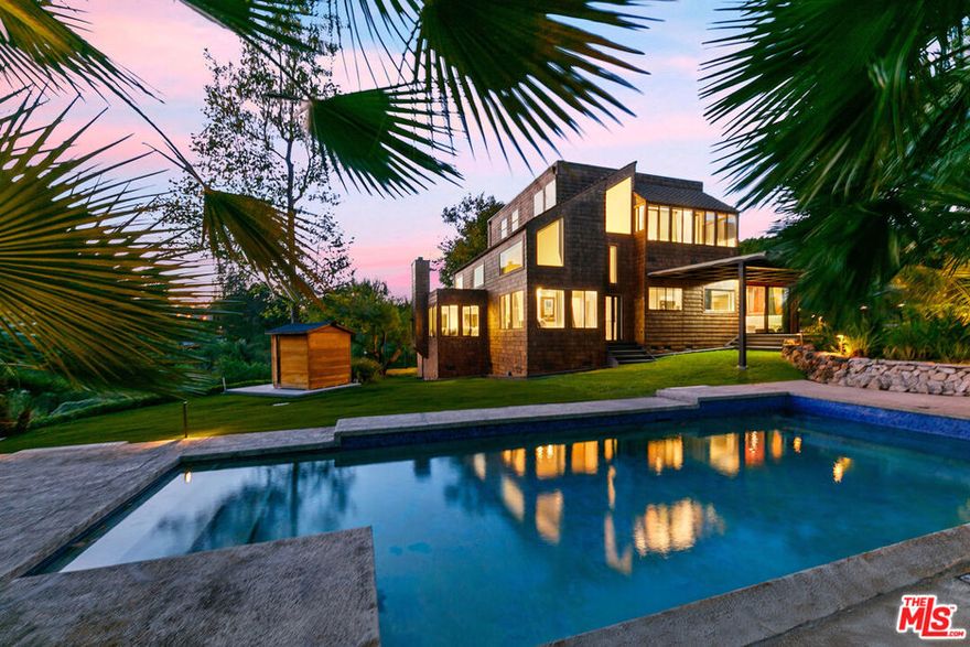 Set behind double gates on one of the most desirable streets in Malibu, this Point Dume oasis includes coveted private access to the surfers' paradise of Little Dume beach with ocean-adjacent parking. The light-filled residence effortlessly marries architectural charm with the relaxed feel of resort living in Malibu. Located on a sprawling acre, surrounded by lush lawns and mature landscaping, this 3-bedroom, 2.5-bath home welcomes you with an inviting formal dining area overlooking a sunken living room anchored by a distinctive fireplace. Large clerestory and canyon-facing picture windows bathe the interiors in abundant natural light, creating a warm blissful atmosphere throughout. The adjacent den features soaring ceilings and expansive windows offering the perfect space for entertaining or unwinding, seamlessly connecting to the lawns, pool, spa, sauna and multiple outdoor terraces. The kitchen adorned with handcrafted tilework, flows into a cozy breakfast nook and a charming bistro room with a banquette perfect for savoring morning coffee in tranquility. Two main-level bedrooms share a bathroom, with one currently serving as a peaceful home office. Completing this level are a stylish powder room and a thoughtfully designed laundry room boasting patterned tile floors, plentiful cabinetry, and a second dedicated refrigerator. Ascend the skylit stairwell to discover a versatile bonus room, originally a loft and now enclosed with glass block for privacy making an inspiring artist studio or creative retreat. The primary suite occupies its own private wing, complete with a fireplace and a serene enclosed patio ideal for yoga or meditation, that overlooks the sparkling pool and manicured gardens. The en-suite bath features dual sinks, a shower, and soaking tub framed by treetop views. The landscaping evokes the feel of a private resort, complete with pool, spa, multiple lounging terraces, a cedar sauna, and lush mature trees including palms, magnolias, pines, melaleucas, sycamores and a 100+ ft redwood. The spacious front yard provides a barbecue area and flat lawn, while the back and side yards frame sweeping canyon views. Adding to the property's versatility is a converted garage offering flexible living space with a private, outdoor lounging area. With rare double-gated entrance, resort-style amenities, and coveted access to Little Dume beach, this home embodies the quintessential Malibu Point Dume lifestyle just moments from Point Dume village. The beach and the surf are waiting for you.