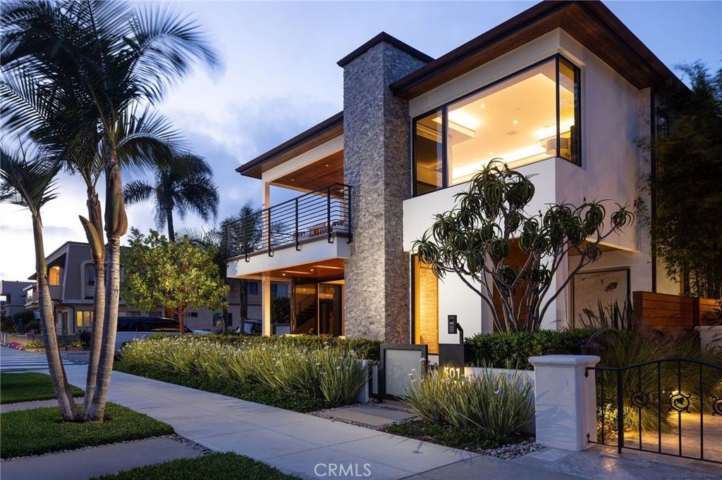 Welcome to 501 Ocean Ave., a striking modern coastal home located just steps from the sand on a premier corner lot in Seal Beach. Built in 2020, this impeccably maintained residence offers refined living with thoughtfully curated finishes and features throughout. This 3-bedroom, 3.5-bathroom home with a den spans two levels of open-concept living. The main level showcases natural stone floors and 9-foot ceilings, while the upper level is finished in rich wood flooring with elevated ceilings, creating a light-filled and airy ambiance. The chef’s kitchen is a true showpiece, featuring high gloss Italian laminated finishes and top of the line Miele appliances, and a second kitchenette in the media room equipped with a refrigerator, freezer, sink and wine closet—ideal for entertaining. The luxurious primary suite is a serene retreat, featuring a wall of disappearing LaCantina doors that open to a private terrace with breathtaking ocean and sunset views, beautifully finished walk in closet and designer fireplace, while the primary bath offers a freestanding tub, dual vanities and a grand walk-in shower. Each additional bedroom is spacious and well-appointed, offering privacy and comfort. The seamless indoor-outdoor flow continues with beautifully landscaped patios, an interior courtyard with a 48-inch fireplace, a mounted outdoor TV, and built-in overhead heaters—perfect for year-round enjoyment. The finished garage is a rare bonus, complete with 24-inch-deep storage cabinetry and a Direct Lift car lift, offering functionality without sacrificing style. Additional amenities include an elevator, safe room/office, whole-house sound system and Control4 automation, instant hot water, a water softener and filtration system, and smart Lutron and Luxor lighting throughout. This is modern coastal living at its finest—meticulously designed, masterfully built, and ideally located just moments from the beach, Main Street dining, boutique shopping, and all that Seal Beach’s charming Old Town has to offer.