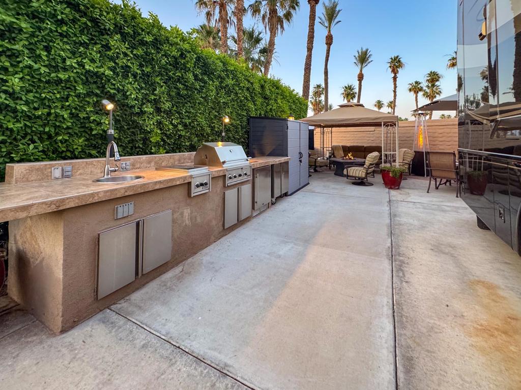 Take your RV lifestyle to the next level with Lot #100, a beautifully maintained luxury site in the heart of Outdoor Resort Indio. This private, peaceful oasis is designed for elevated living, featuring a charming gazebo with a new 10-year top, mounted TV, fire table, and stylish dining area--perfect for entertaining or unwinding in style. The well-equipped outdoor kitchen, complete with stainless appliances including a fridge, Lynx grill, and burner, transforms mealtime into a gourmet experience. Lot space is maximized with pavers and easily accommodates a 45' coach, extra vehicles, and has a dedicated golf cart space. Thoughtful extras like a large storage cabinet, rolling storage, and a private pet area enhance both convenience and comfort. Just a short walk from the clubhouse, pool, cafe, fitness center, and Phase 2 golf course entry, Lot #100 is more than a lot--it's a lifestyle upgrade. Previously rented for three months last season, this standout site offers resort living that truly delivers. At the end of the season, protect your lot with custom Solshades covers for the kitchen, umbrella, pedestal lights, and fire table. Outdoor Resort Indio is a Class-A RV resort.