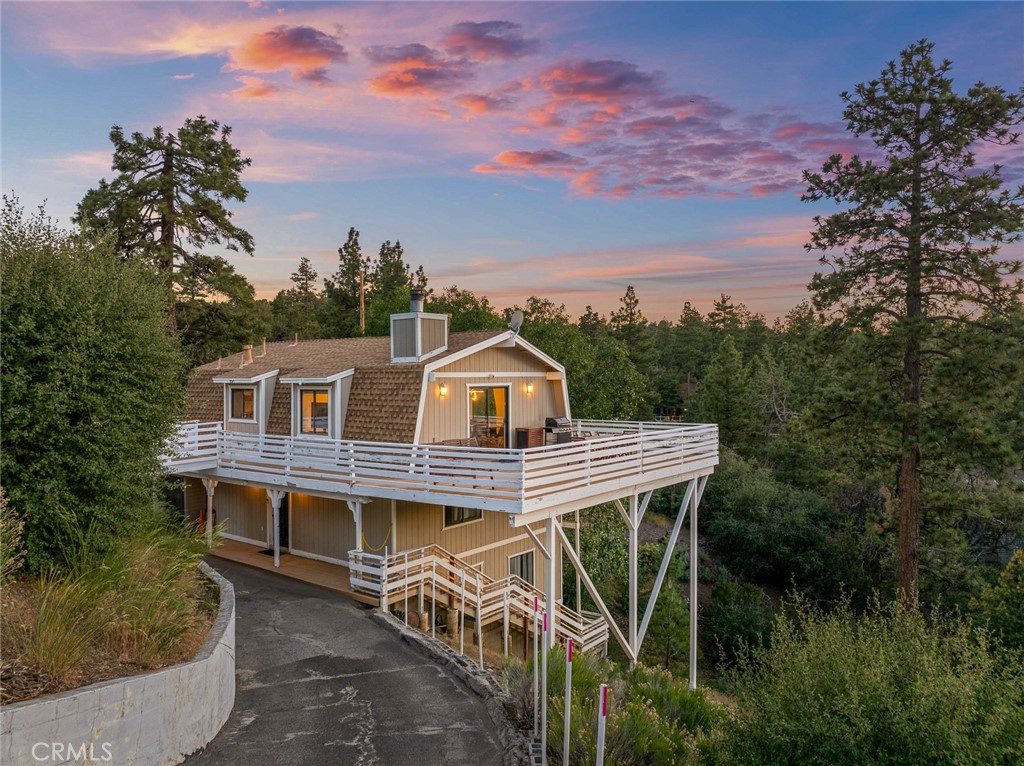 Discover the charms of Big Bear in this remodeled three-story home with mountain views and wraparound deck. With 4 bedrooms and 2.5 bathrooms, the home is perfectly positioned on a quiet street in the desirable Poet's Corner neighborhood. With 1880 sq ft of thoughtfully designed living space, this home blends classic cabin elements with modern finishes. The property has an expansive 9,665 sf lot size. Newer luxury vinyl plank flooring leads you through an inviting, light-filled interior. The top-level living room, warmed by a charming brick fireplace, features sliding glass doors that open to the home's wraparound deck. At the heart of the home, the chef’s kitchen is equipped with plentiful cabinets, butcher block countertops, newer fridge and dishwasher. This space is built for both casual dining and entertaining. The living room is complemented by pendant lighting and newer recessed lighting that adds to the home's refined ambiance. Seamlessly integrating indoor and outdoor living, the lower-level family room opens to the property's horseshoe shaped driveway that parks 5 vehicles. Additional highlights include central heating for year-round comfort and a layout that supports both privacy and flow. Currently a permitted vacation rental with no HOA fees, this home offers excellent income potential for investors or a turn-key opportunity for those looking for a mountain retreat. Whether you're looking for a serene mountain getaway, a full-time residence, or an income-generating property, this versatile home offers it all. Schedule your private showing today and experience the best of Big Bear living.