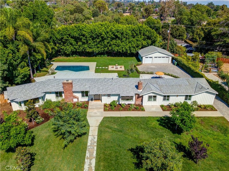 Welcome to this stunning single-level custom ranch-style estate in beautiful Friendly Hills. Situated on a sprawling 27,992 sq. ft. flat, private, and gated lot, this turnkey residence offers timeless charm blended with modern luxury. The home features 4 spacious bedrooms, 3 elegantly designed bathrooms, and approximately 2,710 sq. ft. of fully remodeled living space. A brand-new detached 750 sq. ft. 3-car garage sits behind a private gated entry and paver driveway—an ideal space for a car collection, toys, a future ADU, man cave, game room, or pool house. Step inside and you’re welcomed into the formal living and dining room, showcasing classic wainscoting, a stone fireplace, and built-in shelving, while oversized windows bathe the home in natural light, creating a bright, inviting atmosphere for entertaining or everyday living. The chef’s kitchen is a true showstopper with new stainless steel appliances, farmhouse sink, custom cabinetry, stone accents, and open shelving, and down the hall a large step-down family room with vaulted ceilings offers the perfect gathering space, seamlessly connecting to the dining area with a wall of glass framing the backyard and pool for effortless indoor-outdoor living. Each bathroom has been reimagined with a spa-like feel, including frameless glass showers with designer tile, dual vanities with quartz counters, and brushed gold fixtures, while a freestanding soaking tub beneath a sparkling chandelier creates the ultimate retreat. The primary suite is private and luxurious, while the 4th bedroom with attached bath makes an ideal guest suite or in-law quarters. The backyard is designed for entertaining and relaxation with a resurfaced pool surrounded by mature trees for privacy and a resort-like setting, complemented by a gravel lounge, café-style patio, and expansive lawns that provide space for gatherings, play, and pets. This estate is truly rare, every inch thoughtfully upgraded for both style and function, and just moments from Friendly Hills Country Club with easy access to both Orange County and Los Angeles, the property combines serenity with convenience. Enjoy scenic hills, hiking trails, and Whittier’s charming shops and dining nearby, truly a gem in the heart of Friendly Hills.