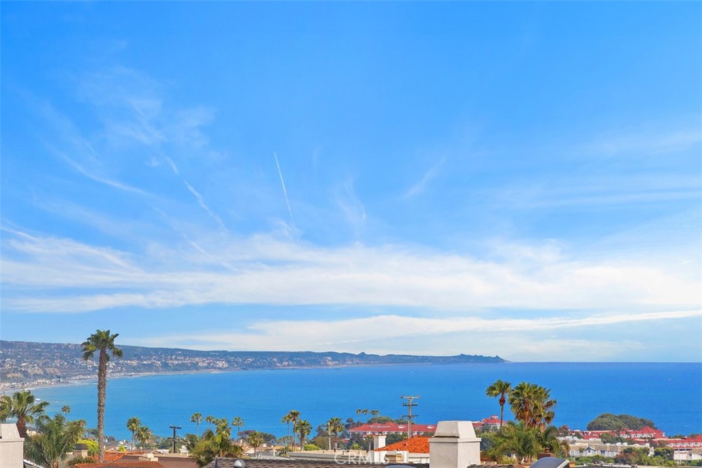 Experience the epitome of coastal luxury in this stunning Dana Point townhome, where panoramic ocean and whitewater views take center stage from both interior and exterior living spaces. Nestled on one of Dana Point’s most private and peaceful cul-de-sac streets, this beautifully remodeled residence offers nearly 2,000 square feet of elevated living, with sweeping vistas from almost every room. Soaring ceilings and natural light greet you the moment you step inside, drawing your eye to the coastline. A striking custom glass-panel stair system sets the tone for the home’s sleek, modern coastal aesthetic, while wide-plank white oak flooring and custom built-ins bring warmth and character throughout. The open-concept layout connects the kitchen, dining area, and living room—each space offering ocean views and seamless flow to a spacious main-level deck designed for sunset dinners or relaxed indoor-outdoor living. The kitchen is a dream for both entertainers and everyday cooks, featuring Electrolux integrated refrigeration, a Bosch induction range and dishwasher, soft-close cabinetry, and an oversized island that brings everyone together. A private back patio just off the kitchen provides a tucked-away space for grilling or unwinding—with direct access to the community pool, spa, and clubhouse just steps away. Upstairs, the spacious primary suite is a calming retreat where you can wake up to ocean views from bed and unwind in a cozy niche perfect for reading, watching TV, or soaking in the scenery. It also includes a private deck, a generous walk-in closet, and a beautifully appointed en-suite bath with a soaking tub and walk-in shower. The second bedroom—on the main level—also enjoys ocean views and sits adjacent to a stylishly updated full bath. Situated on a single-loaded street in a quiet enclave in the Lantern District, this home blends timeless Cape Cod architecture by renowned designer Mark Singer with a coastal contemporary interior and panoramic views stretching from San Clemente to La Jolla. With resort-style amenities and walkable access to Dana Point’s harbor, beaches, shops, restaurants, and scenic trails. This is a rare opportunity to own a beautifully updated home with panoramic views in one of Southern California’s most desirable coastal communities. Coastal living at its finest—all year round!