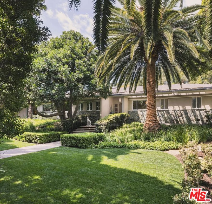 Rare Laughlin Park double-gated, one-story Mid-Century with masterful renovation and landscape design by renowned architects, Tichenor & Thorp. Over 1/2 acre in a prime location of the exclusive Laughlin Park gated community with over 5,700 sqft. Art gallery entry with fireplace. Great scale and design with walnut floors, walls of glass and abundant natural light. Living room with beamed ceilings opens to lush private grounds and entertaining areas. Chef's kitchen with center island and breakfast room opens to large family/media room with Fleetwood pocket doors and custom bookcases. Expansive primary suite with double walk-in closets, beautiful marble and wood-paneled bath and private courtyard garden. Spectacular swimmers pool with arched fountains, lawns, 2-room pool house and majestic specimen trees. A separate gated entrance provides ample onsite parking and 2-car attached garage.