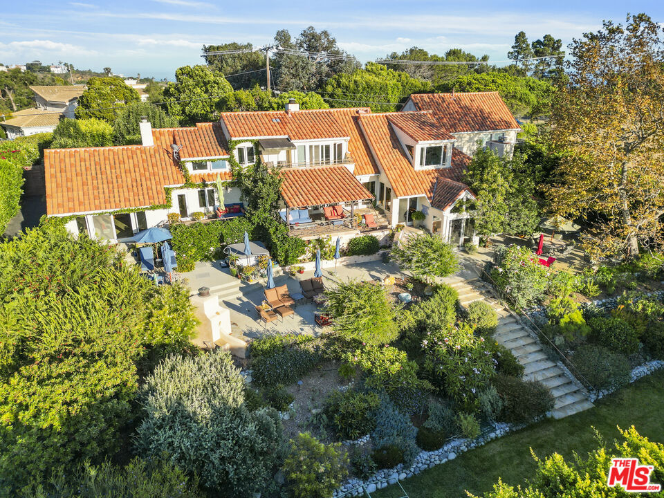 A coastal sanctuary in Zuma Mesa. Perched above the Pacific and set on 1.1 acres with a one-of-a-kind resort-style atmosphere, this estate offers an exceptional blend of elegance, serenity, and California coastal living. Sweeping ocean and canyon views surround the fully walled and gated compound, which includes a 4-bedroom, 3.5-bath main house and a separate, permitted, 1-bedroom, 1-bath guest house, also with ocean views. From the moment you enter the front courtyard, lush, mature landscaping sets the tone for this enchanting retreat. Inside, soaring ceilings and a dramatic sunken living room with a majestic fireplace create a warm yet sophisticated setting, equally suited for intimate gatherings or grand entertaining. The stunning primary suite is a true sanctuary, with a spa-like bath and direct access to the rear patio and gardens, complete with fireplace and spa, where ocean breezes greet you each morning. The cooks' kitchen features a new Miele cooktop, new Bosch dishwasher and center island which opens to a breakfast area and family room, also with a fireplace and access to a covered outdoor dining room. In addition to the guest bedrooms, a loft upstairs offers the perfect space for a home office or gym. Outdoors, the amenities and possibilities are endless: relax in the spa, tend to vibrant gardens, play on the tennis/sport court, sit by the outdoor fireplace, or envision a sparkling pool in the expansive flat grassy yard. Meandering pathways, hidden patios, and colorful landscaping create a rare sense of seclusion in Malibu. The property also includes a three-car garage, currently used as living quarters, along with a state-of-the-art fire suppression system and private water storage. Located in Malibu's desirable gated Zuma Mesa community, this residence is only minutes from pristine beaches, top-rated schools, and Malibu's finest shops and dining. Surrounded by hundreds of acres of the Santa Monica Mountains National Recreation Area with access to miles of hiking and equestrian activities. Convenient community gated entries to both Pacific Coast Highway and Kanan Dume Road ensure effortless connectivity while preserving the tranquility of this hidden gem. Experience the ultimate Malibu lifestyle, where privacy, beauty, and sophistication meet on the endless horizon.
