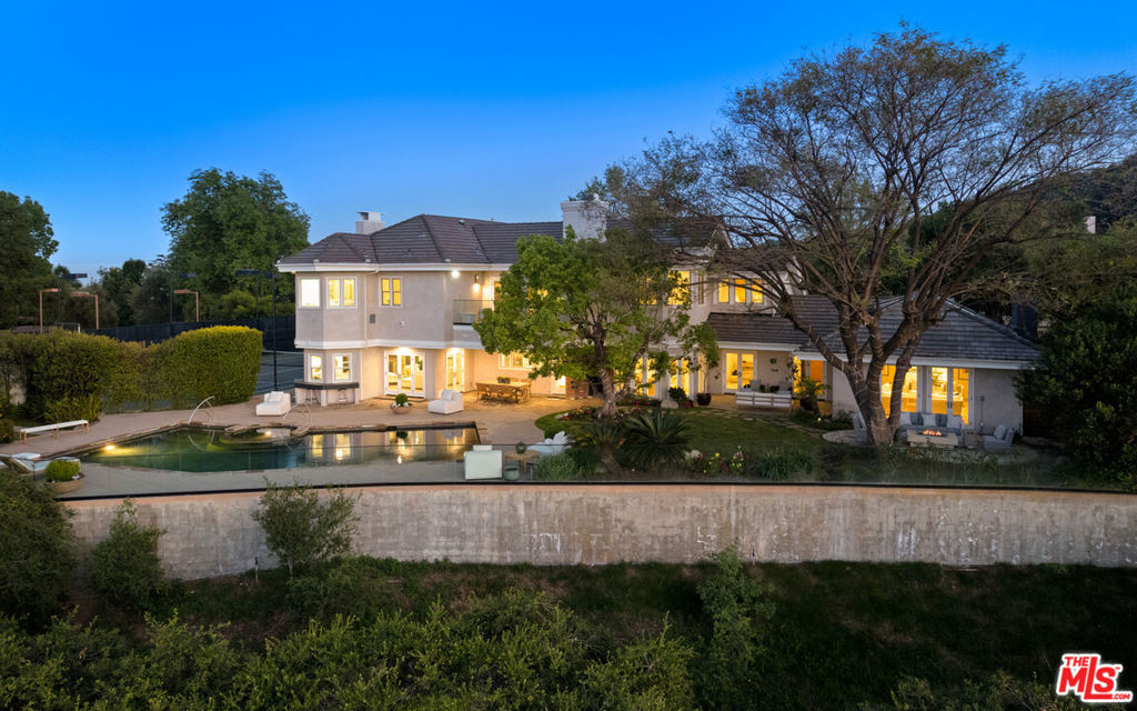 Perched atop a serene, gated street with sweeping views of the canyon and city lights, this exquisite tennis estate is a rare offering for the buyer seeking privacy, sophistication, and exceptional craftsmanship. Behind gates, and nestled within lush park-like grounds, the property offers a full-size, lighted tennis court, a resort-style pool and spa, and a truly seamless blend of indoor-outdoor living. Colorful gardens, vibrant sunsets, and picturesque sunrises over the canyons create a magical atmosphere, while state-of-the-art security and updated systems ensure peace of mind and effortless modern living. The interiors are equally impressive, with soaring wood-beamed ceilings, rich wood and stone floors, and a warm, inviting floor plan. The updated kitchen and bathrooms showcase tasteful design and premium finishes, while expansive windows and skylights flood the home with natural light. The formal dining room features marvelous high ceilings, and an adjoining butler's pantry offers elegance and ease for entertaining. A lovely den/library provides a cozy retreat, and a sophisticated family room includes a full bar and temperature-controlled wine storage. Upstairs, four spacious bedrooms offer comfort and privacy, including a massive primary suite that is a true sanctuary. It features a beautiful adjoining reading room, panoramic views, and a stunning oversized bathroom with a standalone soaking tub overlooking the canyon, a sauna, and dual walk-in closets. A private maid's quarters on the lower level adds versatility and convenience. Outdoors, the detached cabana, mature fruit trees, and multiple entertaining areas offer endless possibilities. An outdoor bathroom sits adjacent to an ideal location for an ADU conversion, perfect for guest accommodations or a studio. A three-car garage and generous motor court provide ample parking for residents and guests alike. This is a signature property where timeless design meets modern luxury, just moments from both Westside and Valley studios, entertainment, private schools, and business centers. Welcome to 3123 Stone Oak Drive, an extraordinary estate to be cherished for generations.
