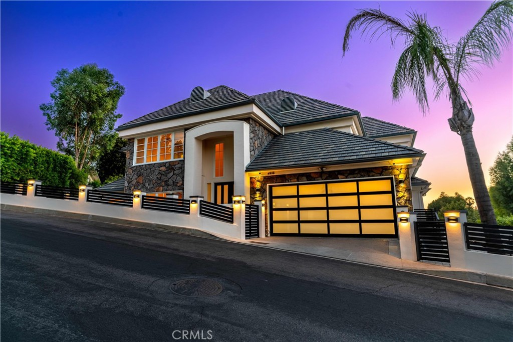 Nestled south of Ventura Boulevard in Tarzana’s exclusive hills, this impeccably renovated 5-bedroom, 3.5-bath estate offers approximately 4,352 sq ft of luxury living on a 16,126 sq ft lot. A bold modern façade with new stucco-and-iron fencing, a sleek contemporary garage door, and an elegant double-door entry sets the tone before you even step inside. The expansive interior has been thoughtfully upgraded with premium flooring, smart home tech (iPhone-controlled lighting, Nest thermostat, smart outlets), and a show-stopping designer kitchen—fully reimagined with custom soft-close cabinetry, a waterfall-edge quartz island, sleek glass-tile backsplash, integrated wine fridge, double ovens, and a professional-grade stainless steel appliance suite. Downstairs bathrooms have been fully remodeled with sophisticated tilework and fixtures. High ceilings, large windows, and skylights invite abundant natural light into a flowing floor plan that includes formal living and dining rooms, a spacious family room, and a large downstairs bedroom ideal for guests or a home office. The primary suite is a private retreat with a fireplace, massive walk-in closet, and spa-quality bath. Step out back to a private entertainer’s deck framed by a brand new iron fence and take in serene mountain views – perfect for evening gatherings or peaceful mornings. Additional highlights include dual-zone HVAC, custom built-ins, a wet bar, and ample storage. Located within the boundary of top-rated Wilbur Charter Elementary and Gaspar De Portola Middle School, this is your chance to own a showpiece home in a premier location – offered at $2,300,000, priced to allow the next owner to add their final touch to an already exceptional renovation.