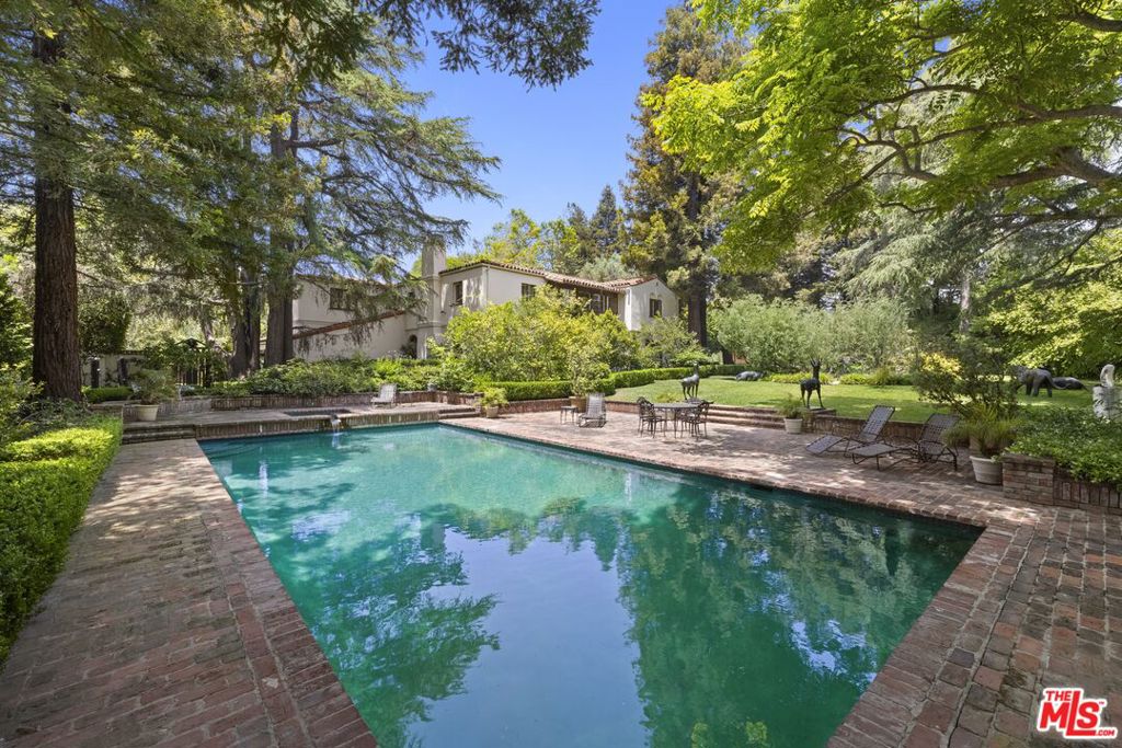 A once-in-a-lifetime opportunity in the heart of Brentwood Park, this blue-chip estate spans over 1.3 acres of flat, sprawling grounds; an offering of extraordinary scale and significance in one of Los Angeles' most prestigious neighborhoods. The expansive setting feels like a world unto itself, with rolling lawns, lush gardens, multiple patios and sitting areas, and a tranquil pond that together create a peaceful atmosphere unmatched among Brentwood's grand estates. A full-size tennis court and oversized pool provide an ideal backdrop for recreation and entertaining. Gated and enveloped by mature hedging, the property offers exceptional privacy and a prime location south of Sunset Boulevard.At the heart of the property stands a romantic Spanish-style residence, rich with warmth, character, and timeless architectural detail. Beyond the gracious foyer, a soaring double-height family room with floor-to-ceiling windows looks out over the magnificent grounds. Large-scale formal living and dining rooms on either side of the foyer bring elegance and versatility, while a sophisticated wood-paneled study offers a quiet retreat. The kitchen is both functional and beautiful, featuring a center island, a generous butler's pantry, and effortless flow to a sunlit patio. A bedroom or office is situated next to the kitchen. Upstairs, there are five spacious bedrooms, each with an ensuite bathroom, including a luxurious primary suite with two full bathrooms and substantial closet space. Toward the rear of the property, a charming standalone library with an attached dry sauna adds a unique and thoughtful touch.