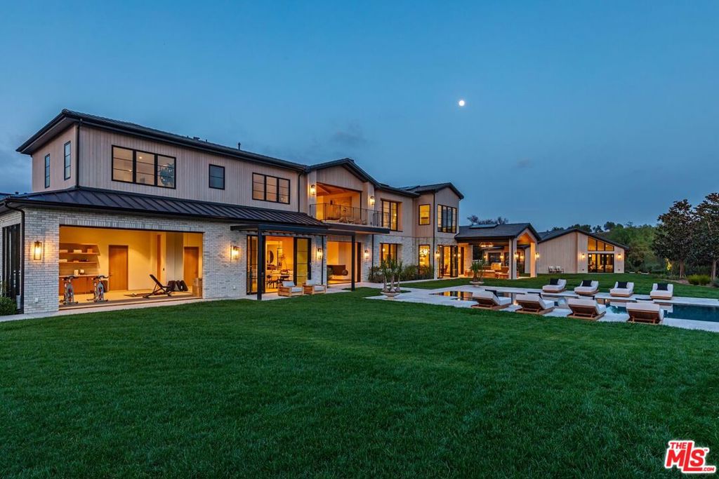 Sited at the end of one of Hidden Hills most coveted cul-de-sacs, this brand-new custom-built estate features 8 bedrooms, 12 bathrooms, with a private guesthouse on a rare, 2-acre view lot. Featuring sweeping views and meticulous craftsmanship, the home is a product of 3+ years of design and construction by one of the community's most prolific builders. It boasts a luminous open floor plan with soaring ceilings, grand scale, and unique design elements such as a commanding, floating, spiral staircase. Highlights include a chef's kitchen with double islands, an additional prep kitchen, and a sunlit breakfast room, flowing seamlessly into the spacious family room featuring open beamed ceilings, a stone fireplace, and walls of glass that open to a large, covered patio complete with a full outdoor kitchen. Additional luxury living spaces include a formal dining room with a glass-encased wine wall, custom-built office, bespoke home theater with acoustic paneling & back-lit coffered ceiling, plus an adjoining lounge/game room with a wet bar, and a resort-like gym/spa with a motorized opening wall, massage area, and luxurious bath with steam shower & sauna. Seven generous ensuite bedrooms complete the main residence, inclusive of the luxurious primary suite featuring wood-clad vaulted ceilings, a stone fireplace, dual bathrooms with skylights, dual boutique-style custom closets, and a large private patio perfect for enjoying the stunning sunset views. The resort-like backyard is a true entertainer's paradise featuring various grassy lawns, a zero-edge pool & spa with a large Baja shelf, plus mature and private landscaping. Perfect for an art lover or car collector, the home comes with dozens of trophy art walls, a motor court, and a well-appointed garage for 7 cars. This home epitomizes the pinnacle of luxury indoor-outdoor living in one of the most prestigious, guard-gated celebrity communities in Southern California.